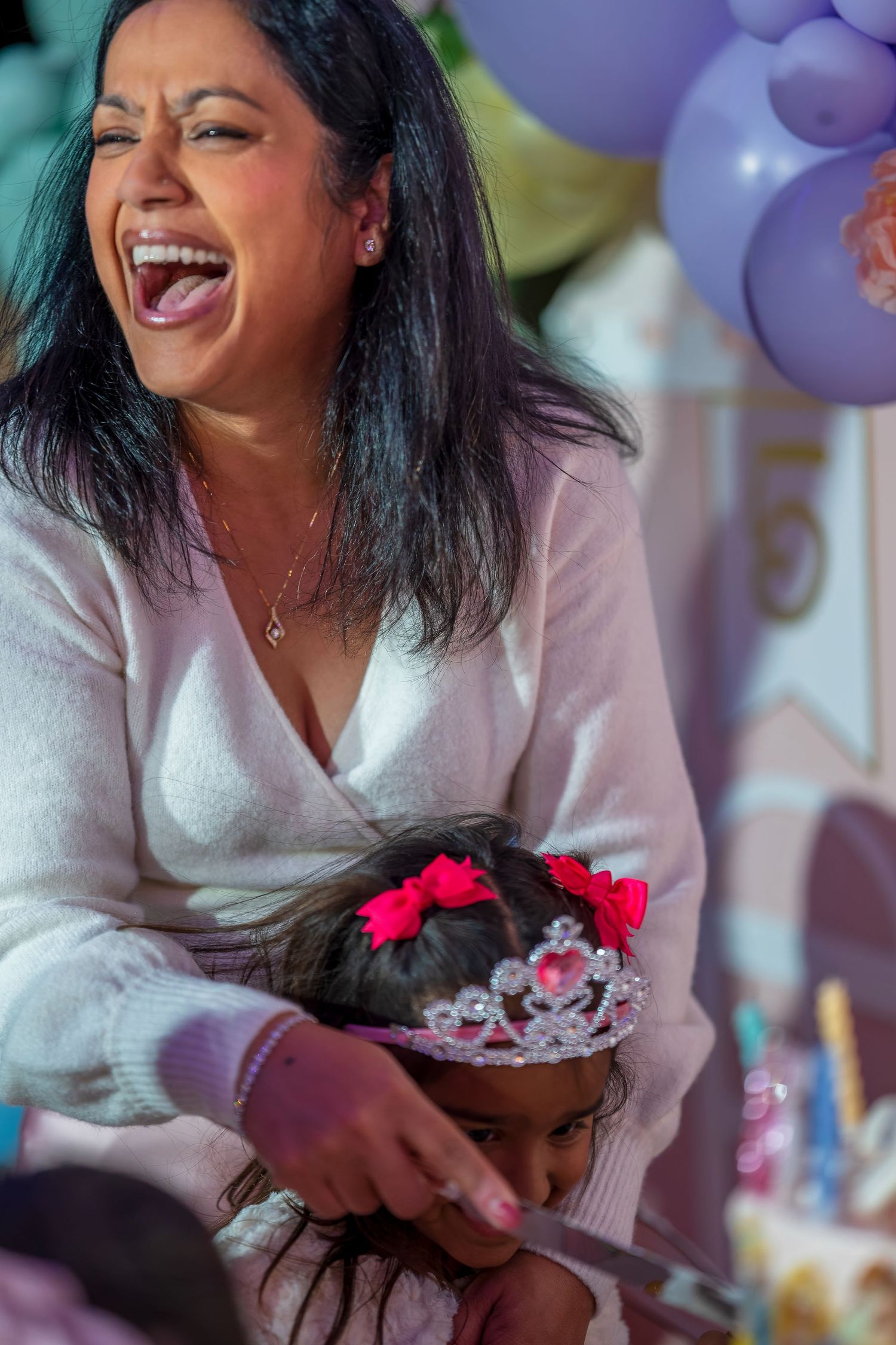 A candid moment of joy and laughter during a birthday celebration with purple balloons.