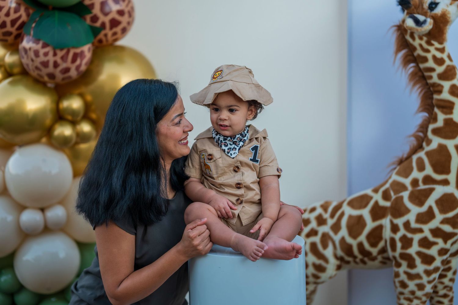 Family photo against a safari party backdrop with gold and white balloons and giraffe decorations.