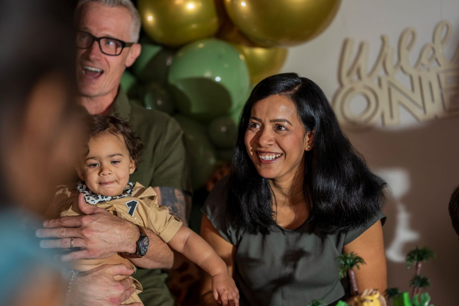 A happy family moment during a birthday celebration with gold balloons in the background.