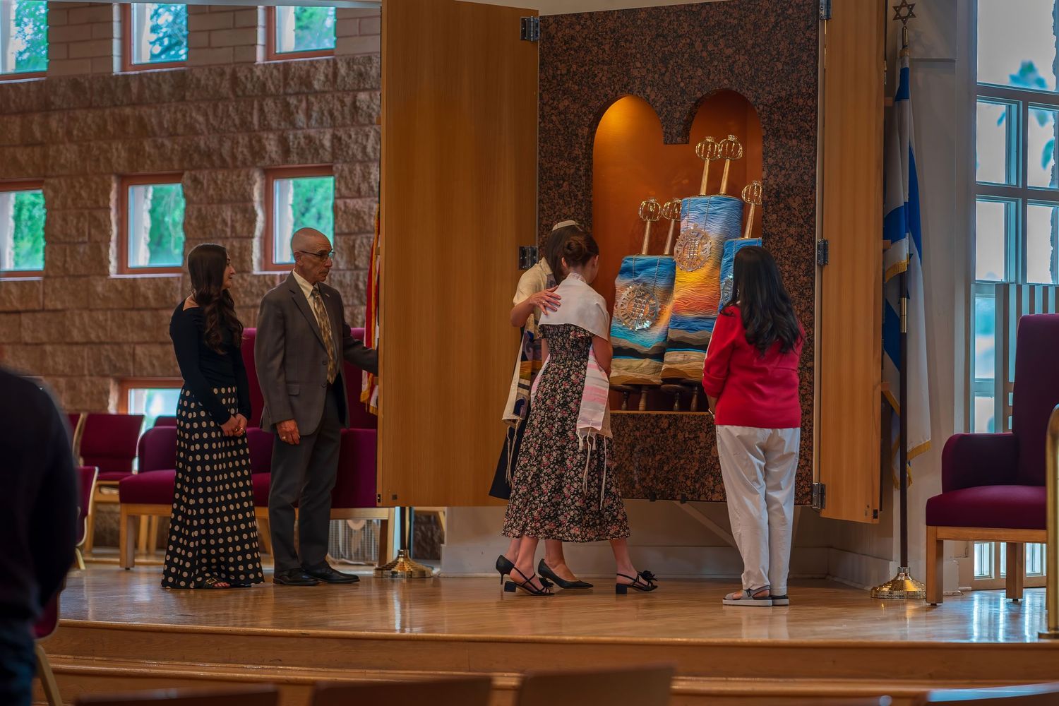 People gathered around colorful artwork on an easel in an elegant indoor venue with warm stone walls.