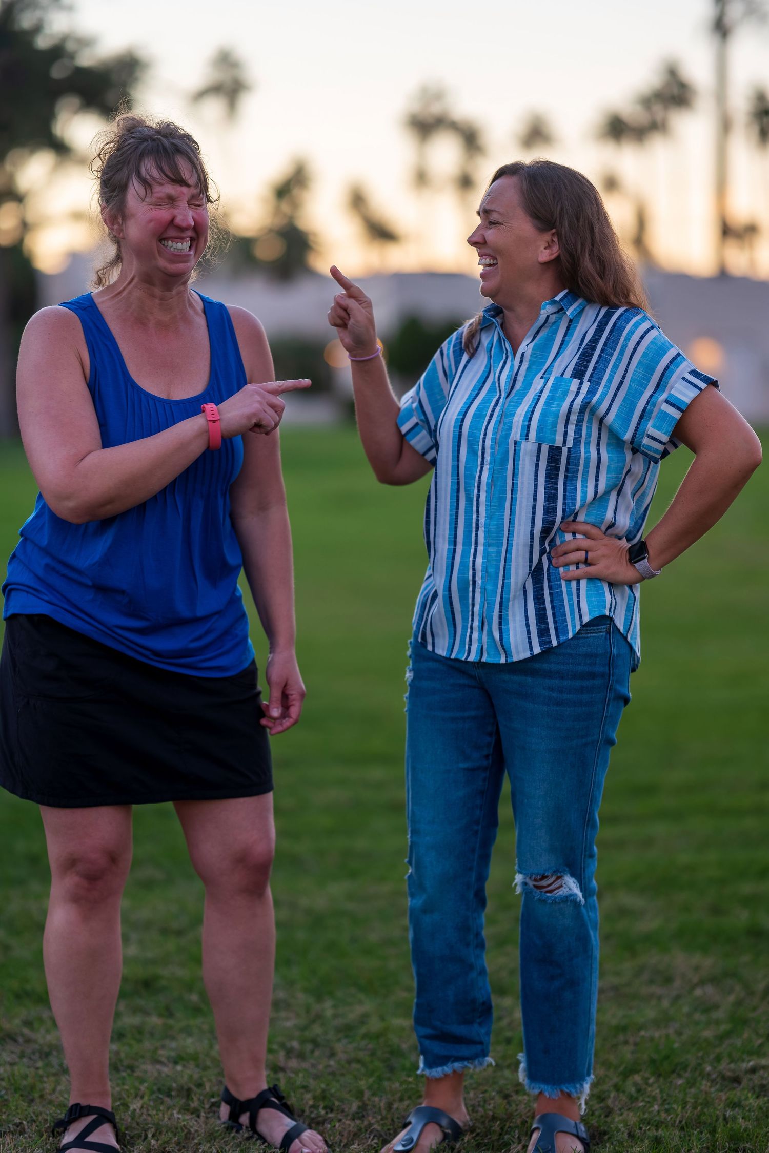 Two people in blue outfits share a joyful moment together outdoors at sunset.
