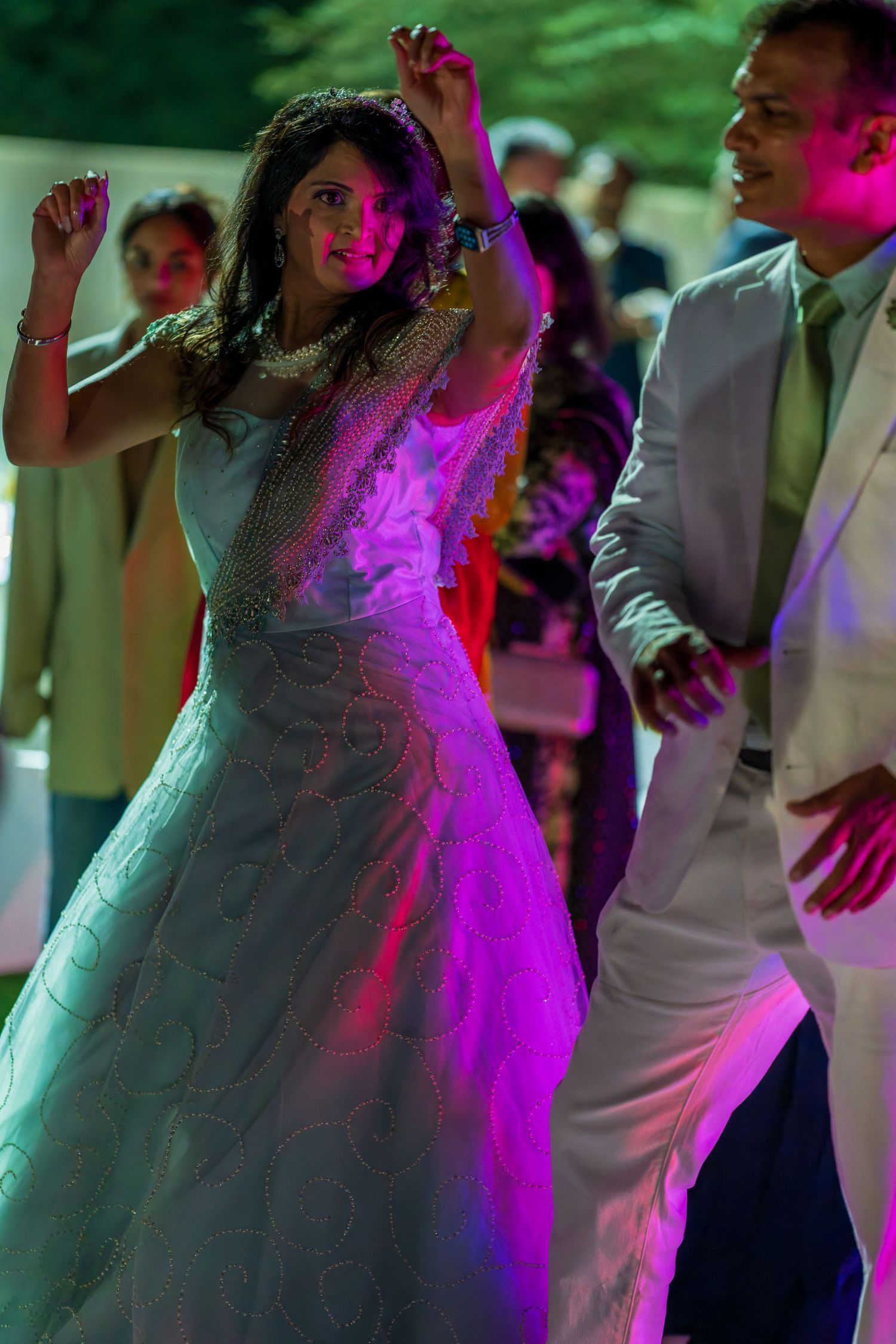 Dancers moving energetically on a dance floor under vibrant purple and pink lighting.