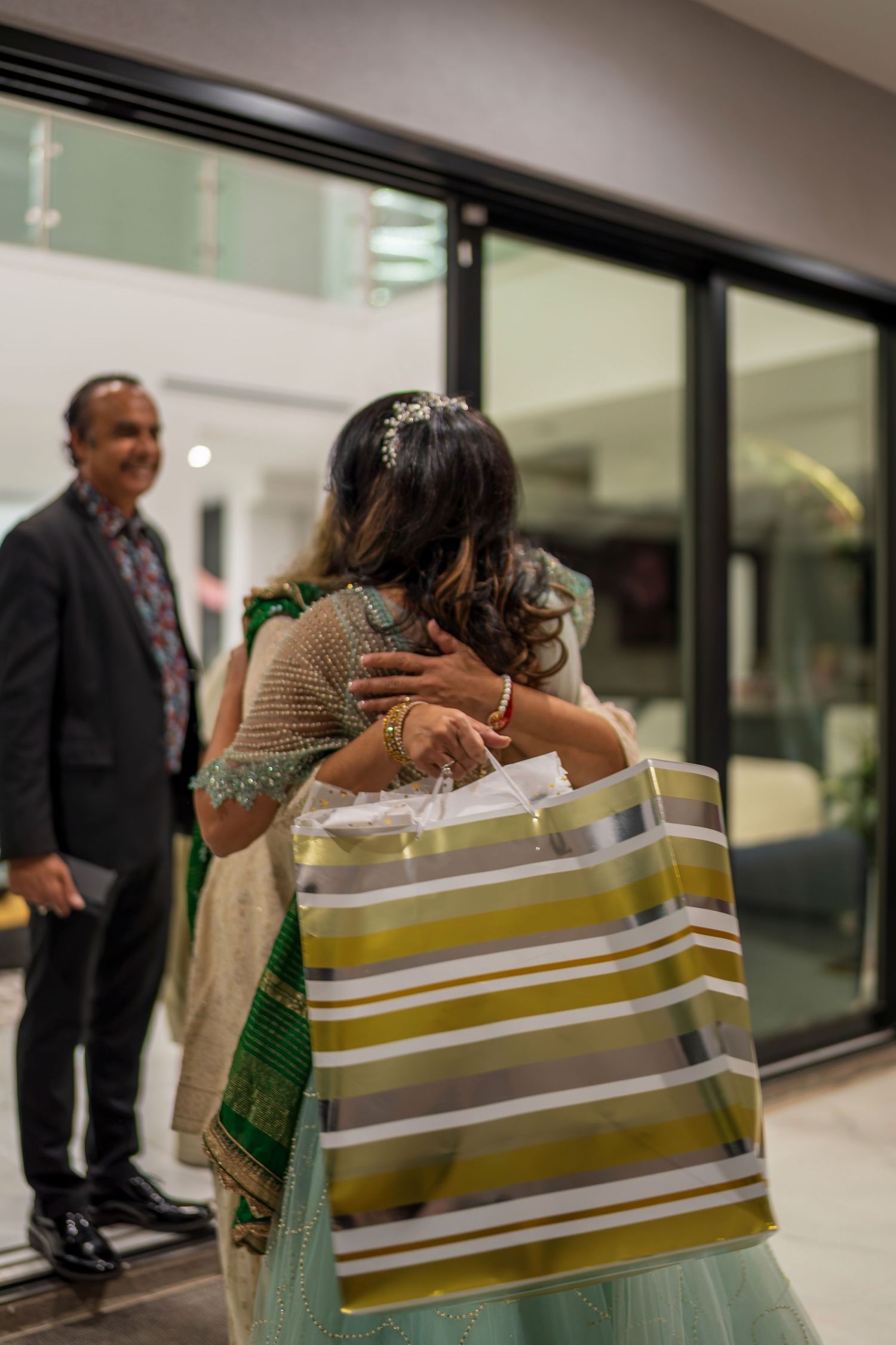 An emotional embrace at an event with a striped shopping bag visible.