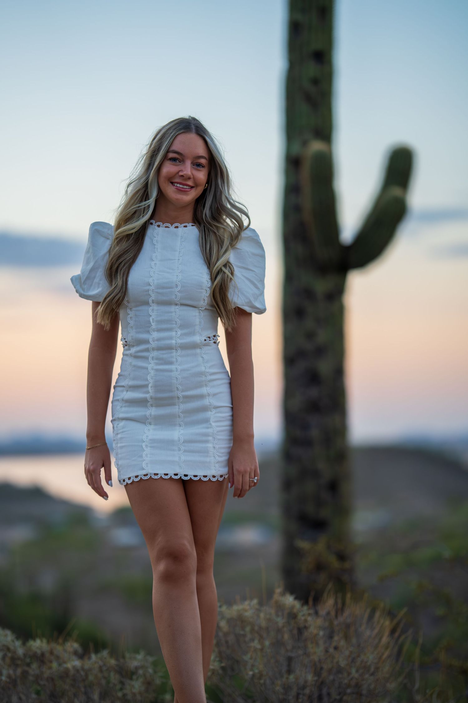 Casual portrait session in white dress with desert scenery and fading sunlight.