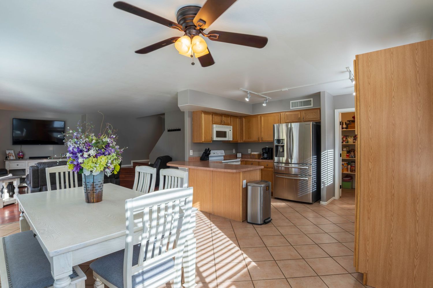 Spacious kitchen and dining area with tile floors, ceiling fan, island, stainless steel appliances, and oak cabinets.