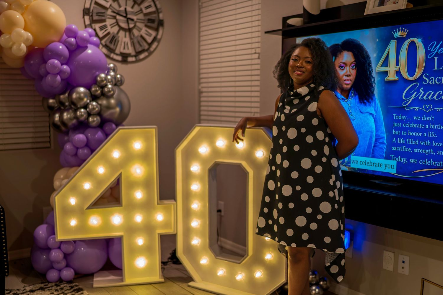 Woman celebrating 40th birthday party with marquee number balloons and purple gold decorations.