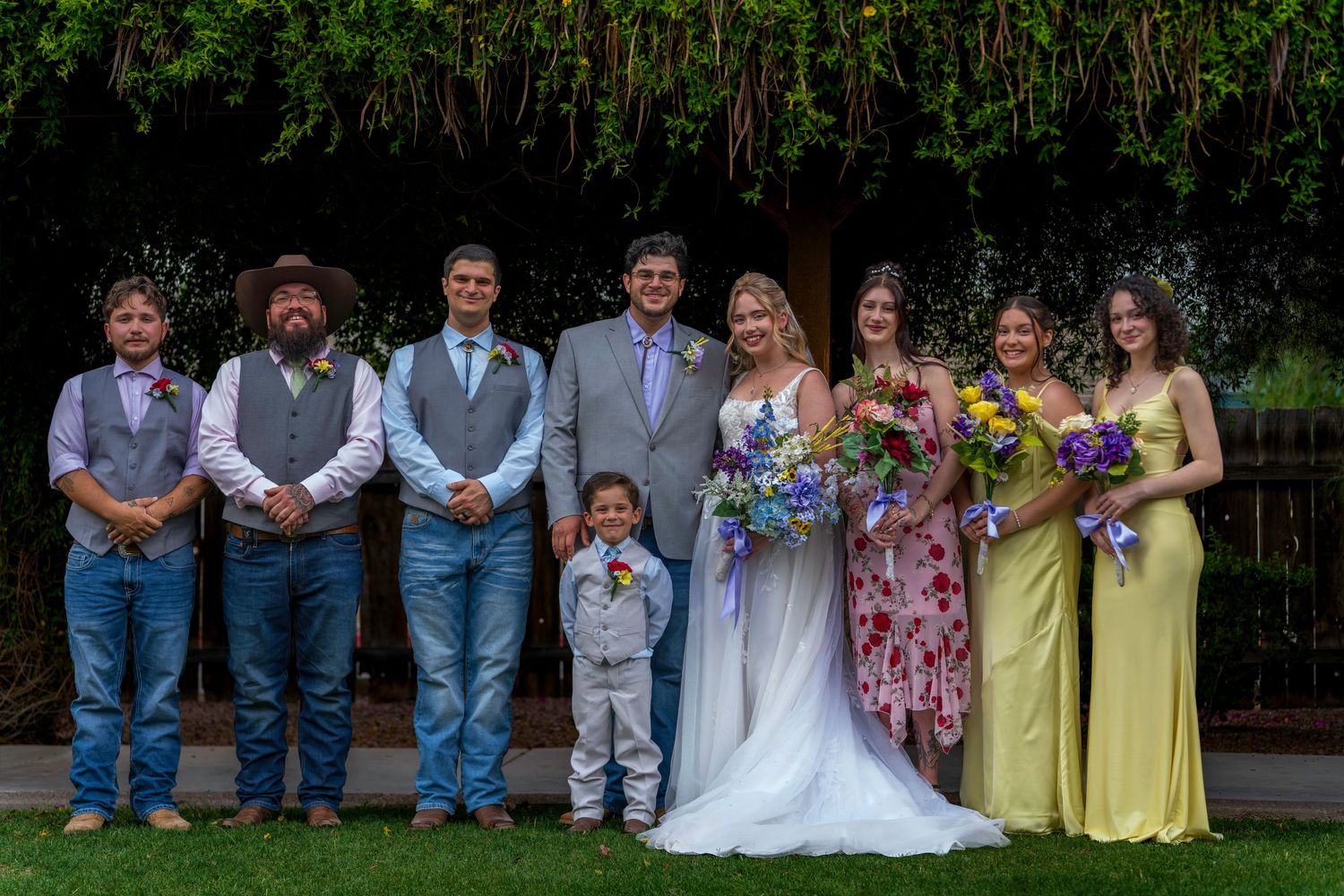 Wedding party group portrait with bride, groom, groomsmen, and bridesmaids outdoors.