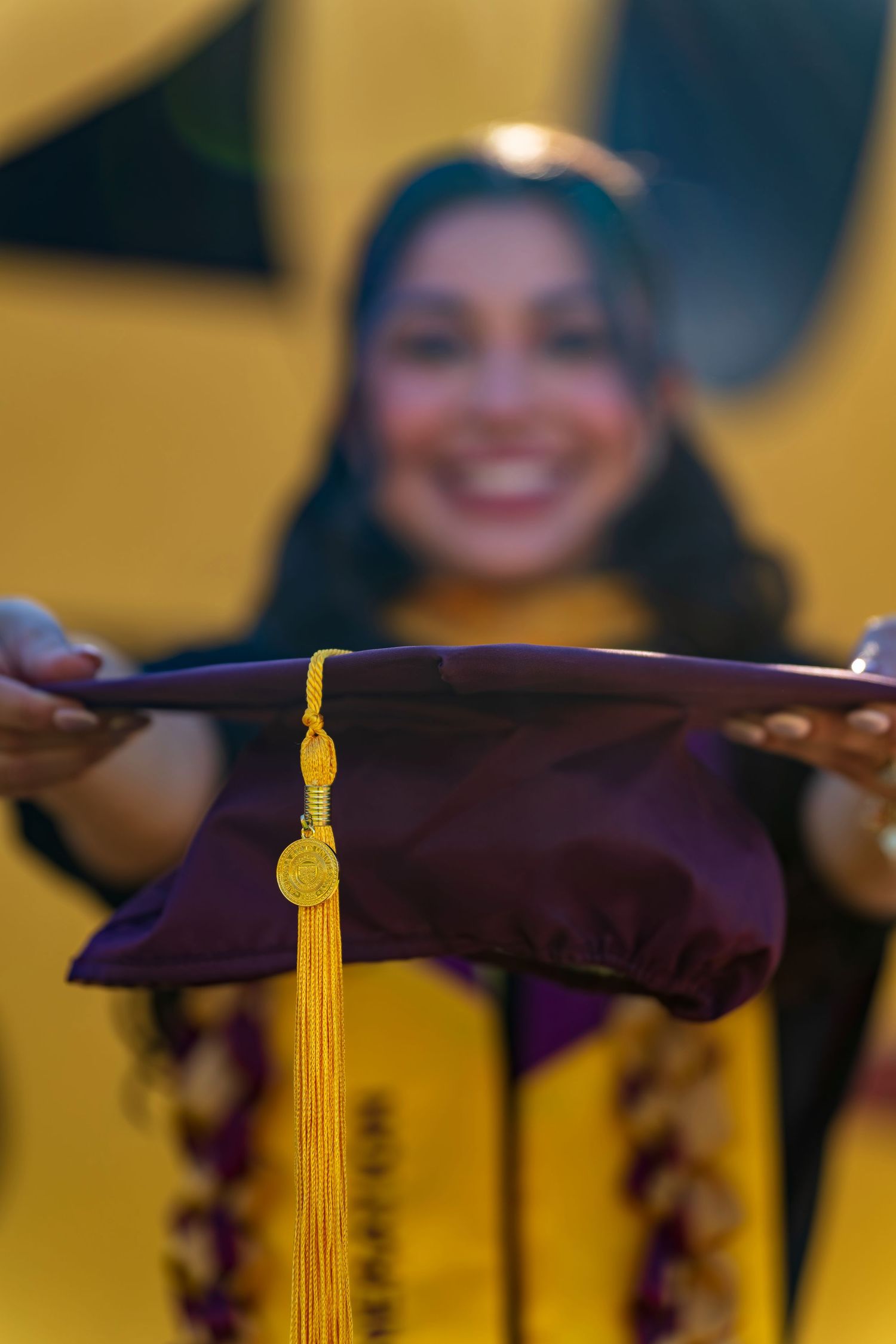Close-up of graduation caps with gold tassels against bright yellow background.