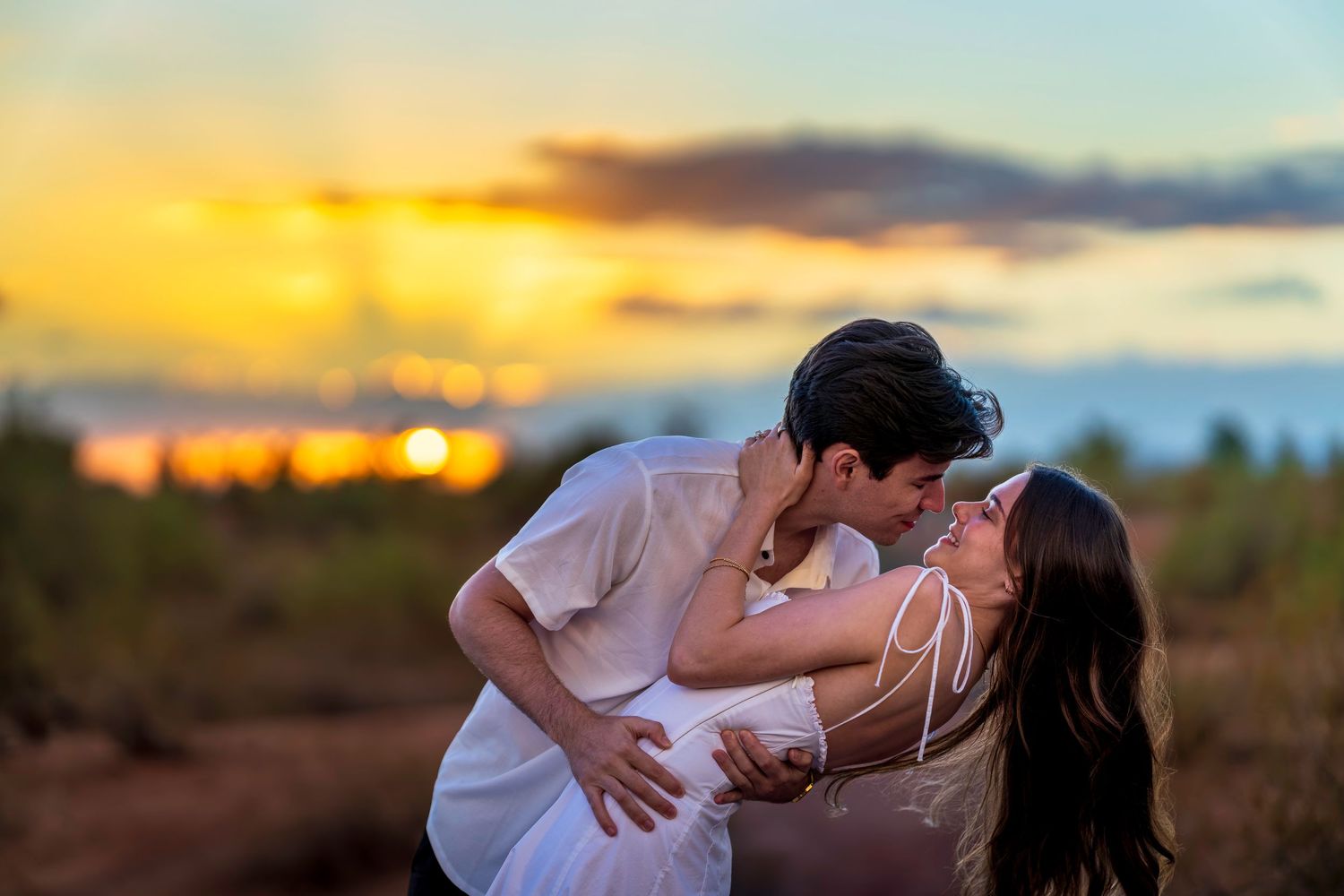 A romantic desert photo session with a couple against a dramatic sunset sky.