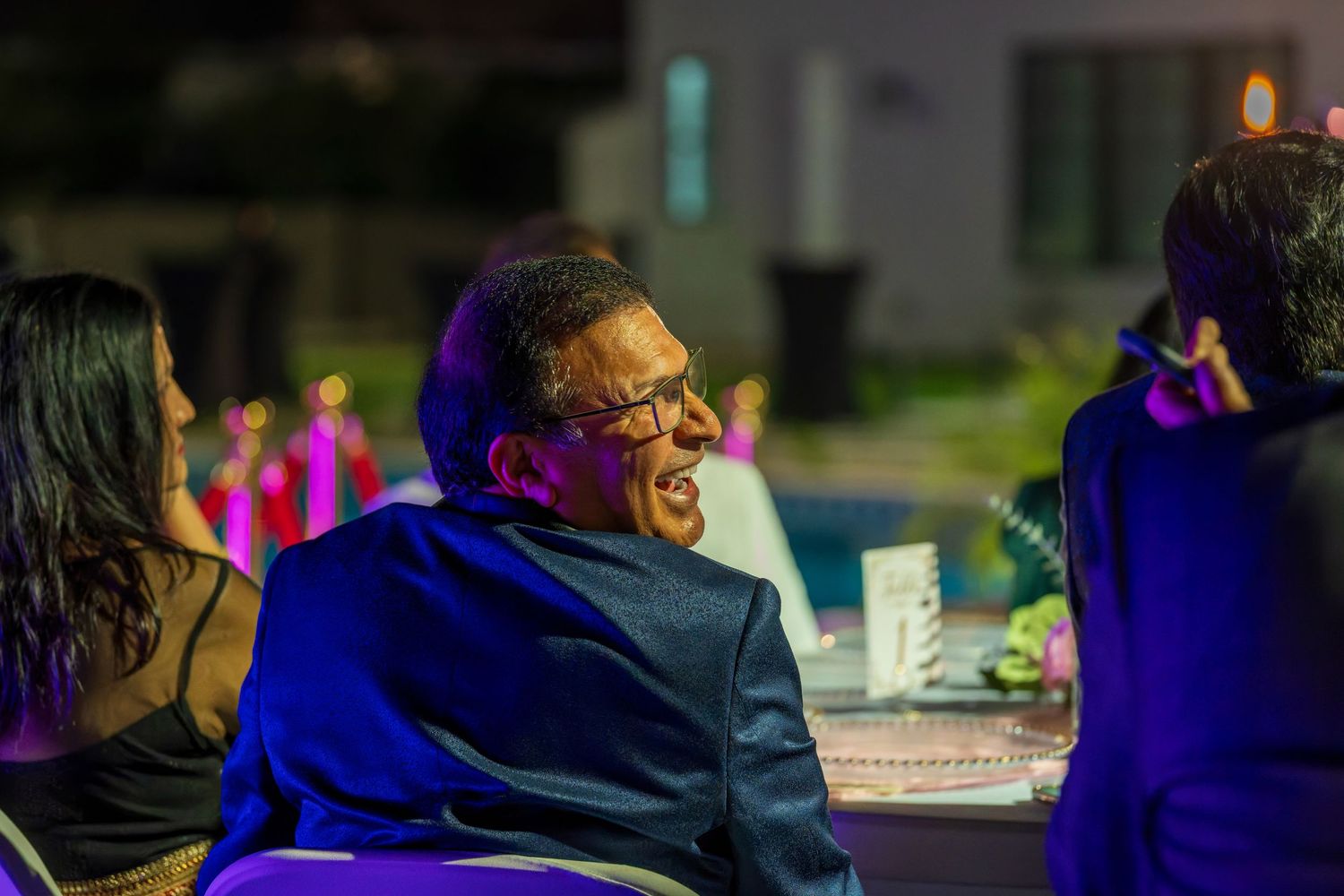 Guest enjoying themselves at an outdoor evening celebration with colored lighting.