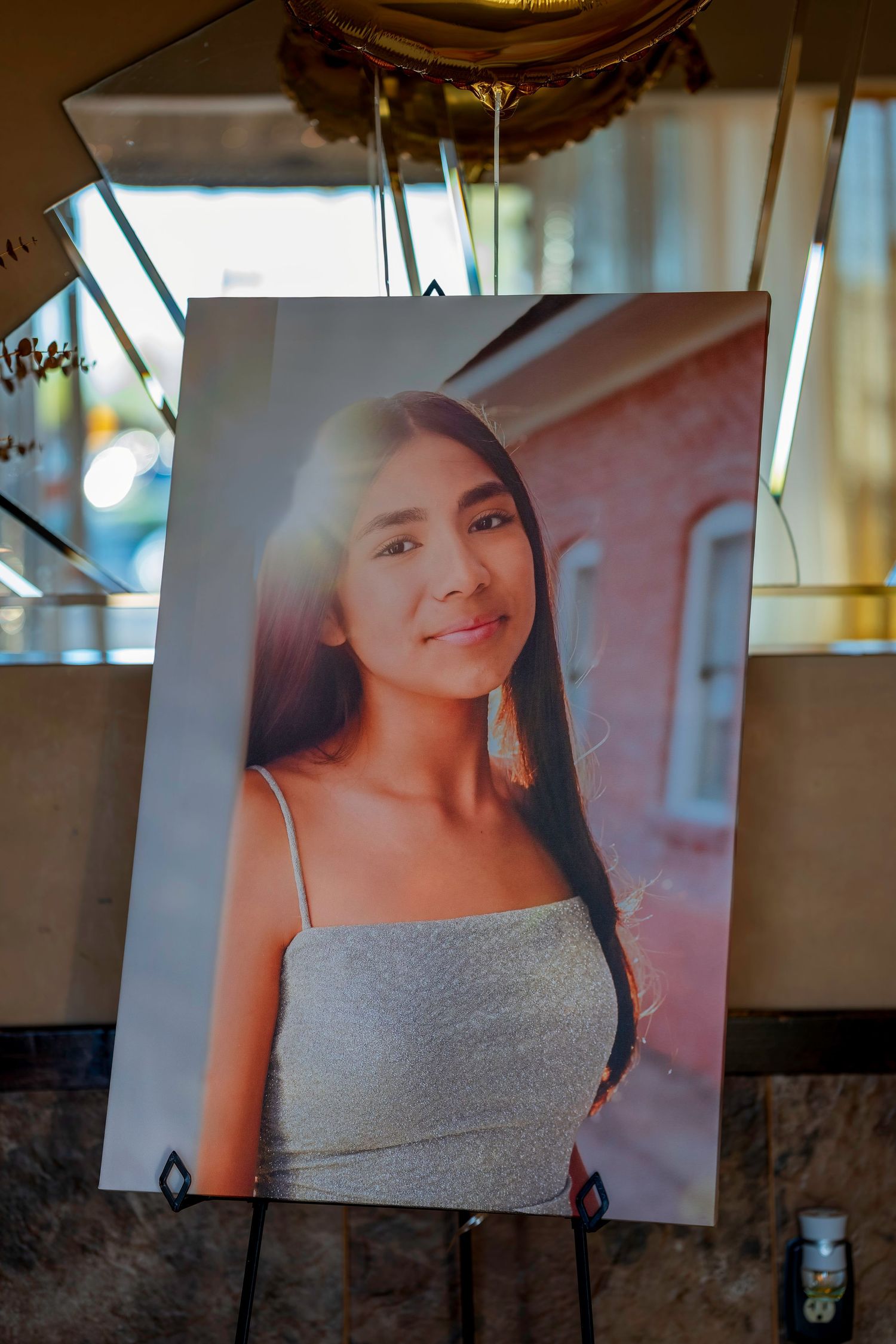 Portrait photo displayed on an easel of a young Latina woman smiling in a gray spaghetti strap top.