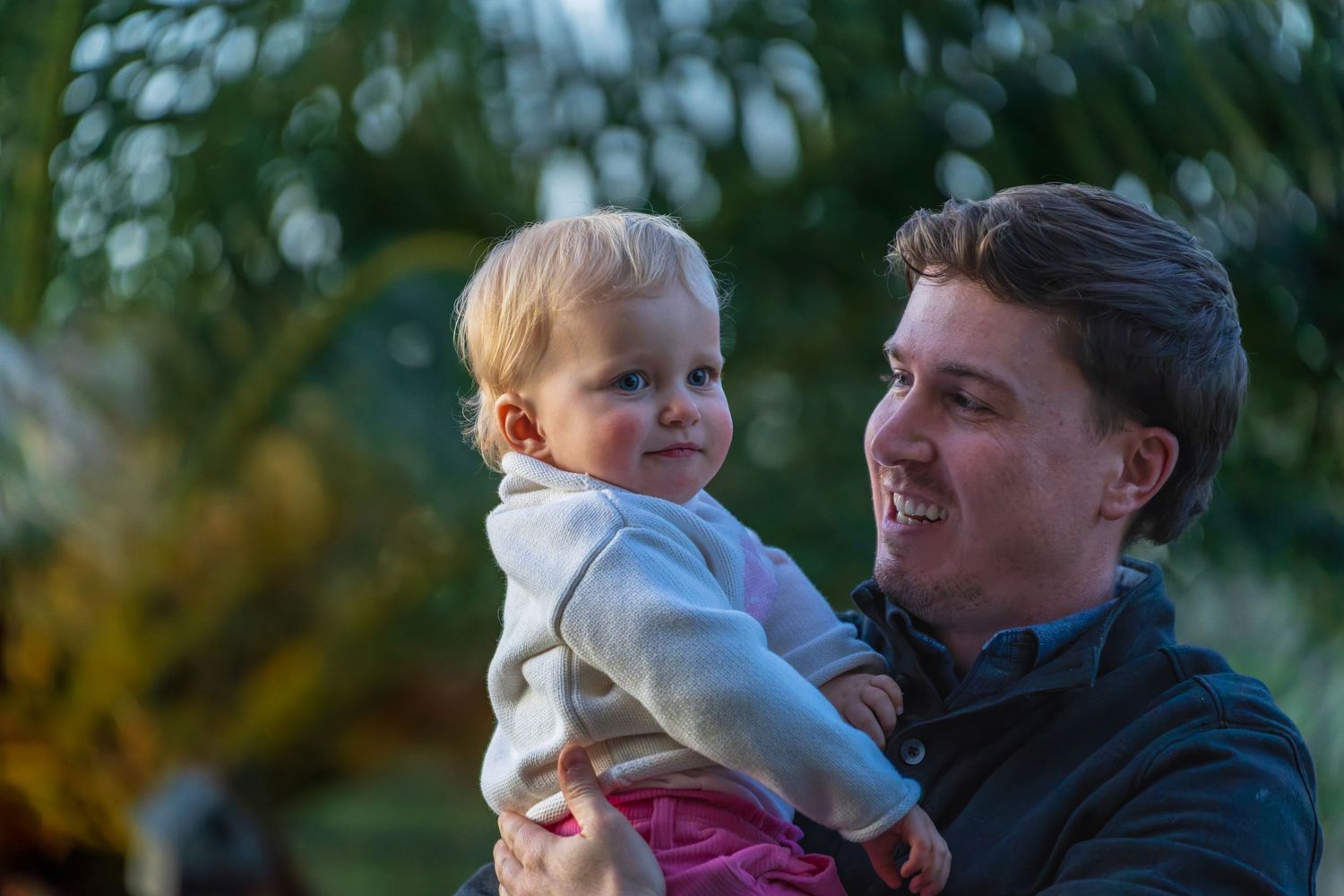 A tender moment between parent and child against a blurred green background.