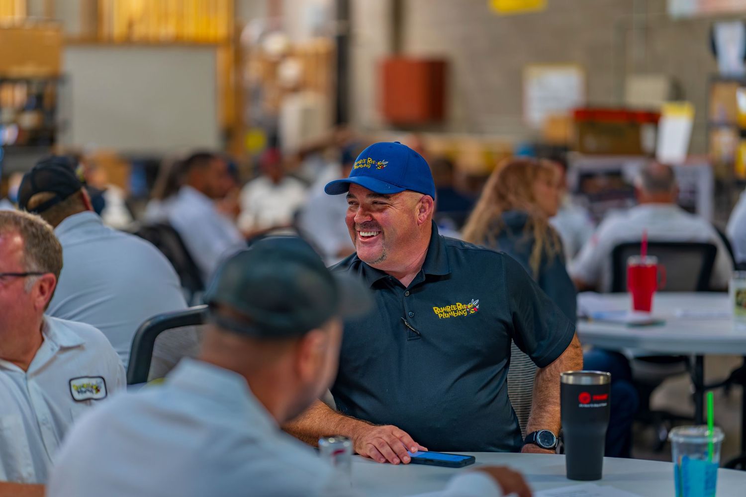 Employee in blue cap engaging in conversation during a company gathering.