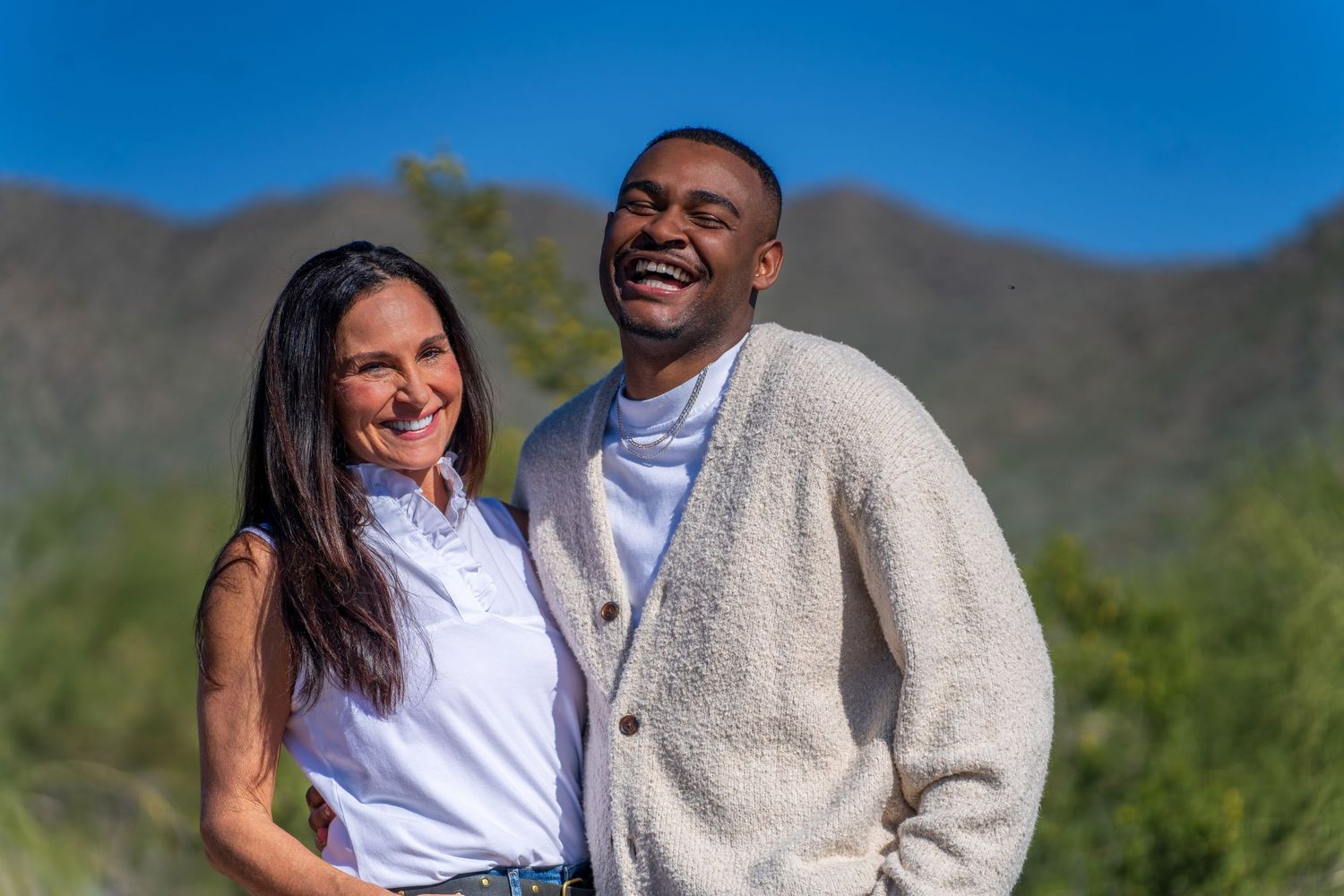 Couple sharing intimate moment outdoors with desert mountains in background.