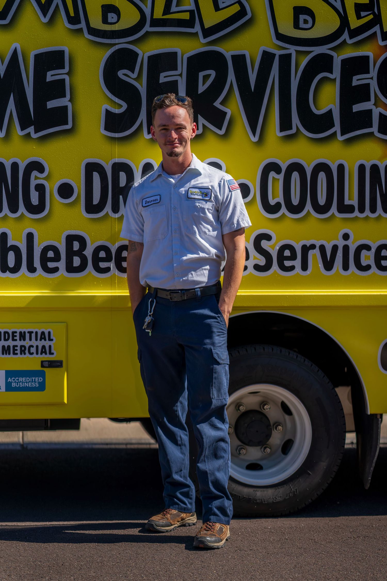 Service technician standing beside yellow Bumble Bee Home Services vehicle.