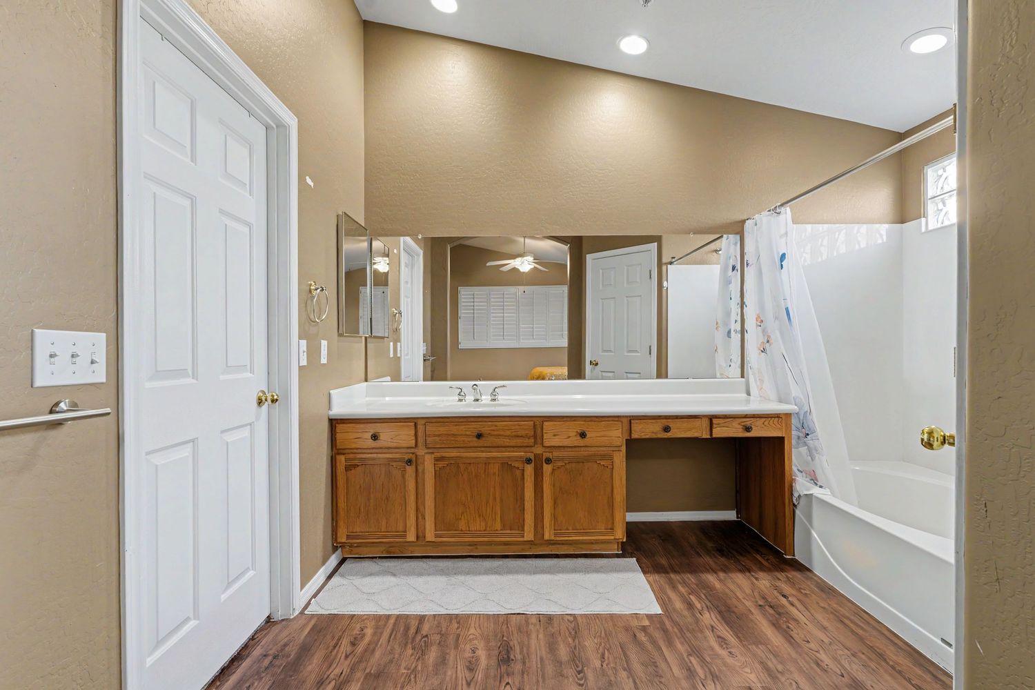 Master bathroom featuring wood cabinets, dual vanity, soaking tub, walk-in shower, and hardwood floors.
