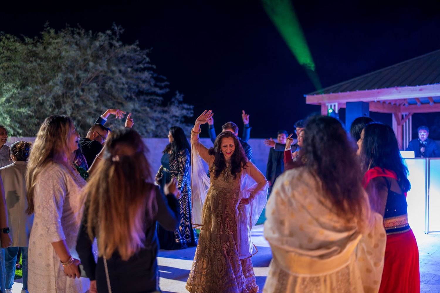 People dancing and celebrating at a nighttime party with colorful lighting effects.