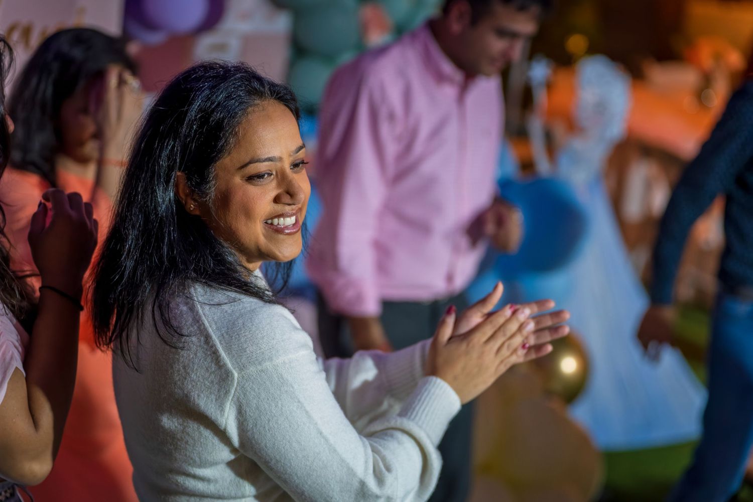 People celebrating joyfully at an indoor party with colorful balloon decorations.