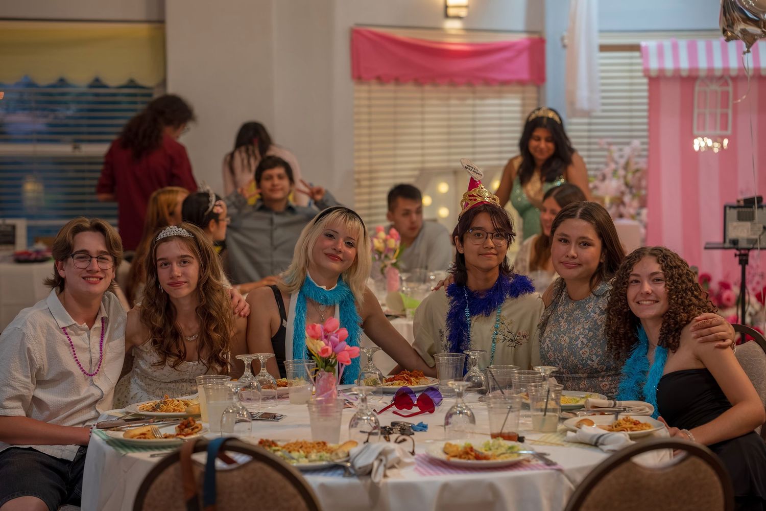 A group enjoying a celebratory dinner at a decorated table with plates of food.