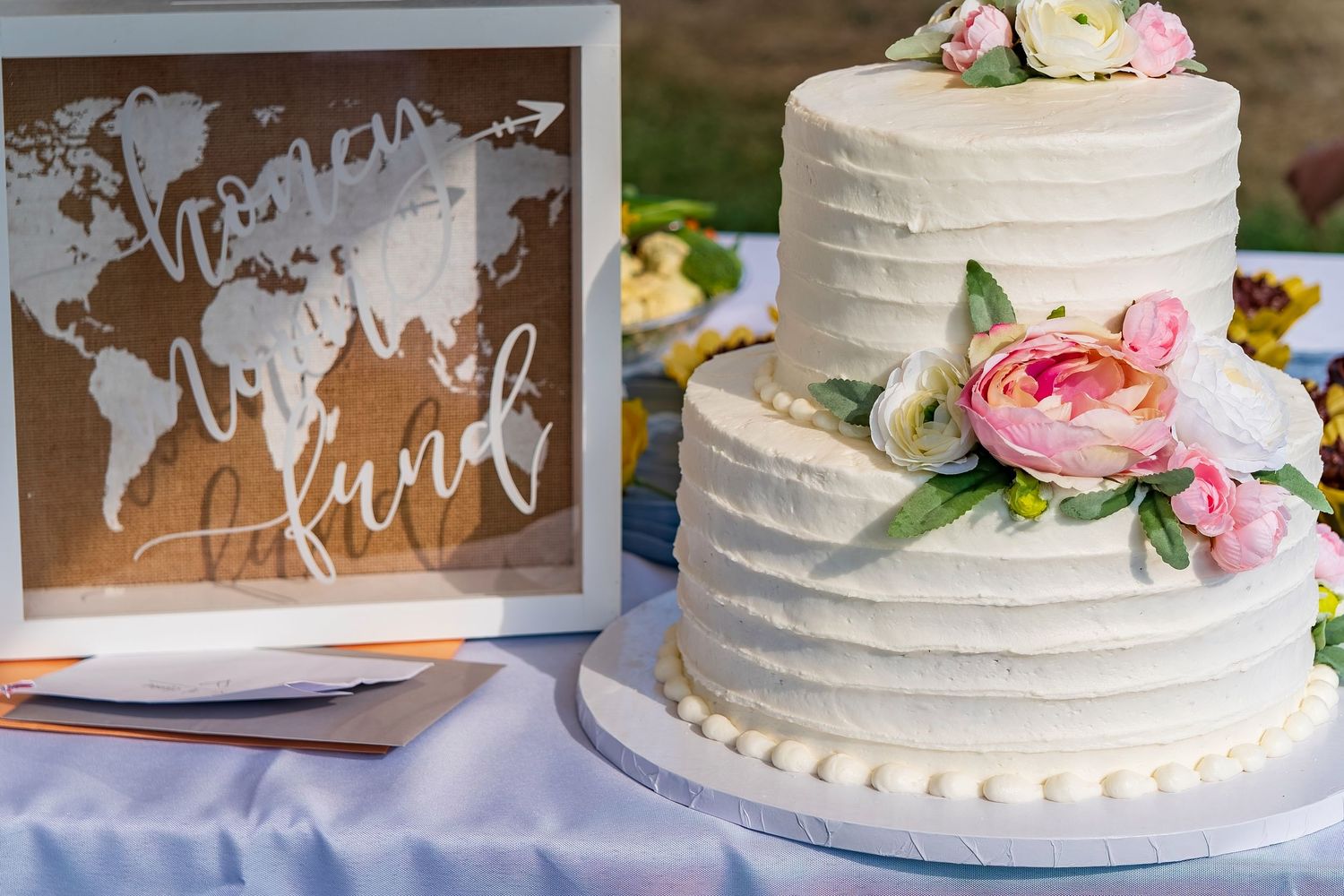 Elegant tiered wedding cake with white frosting and pink floral decorations on display.