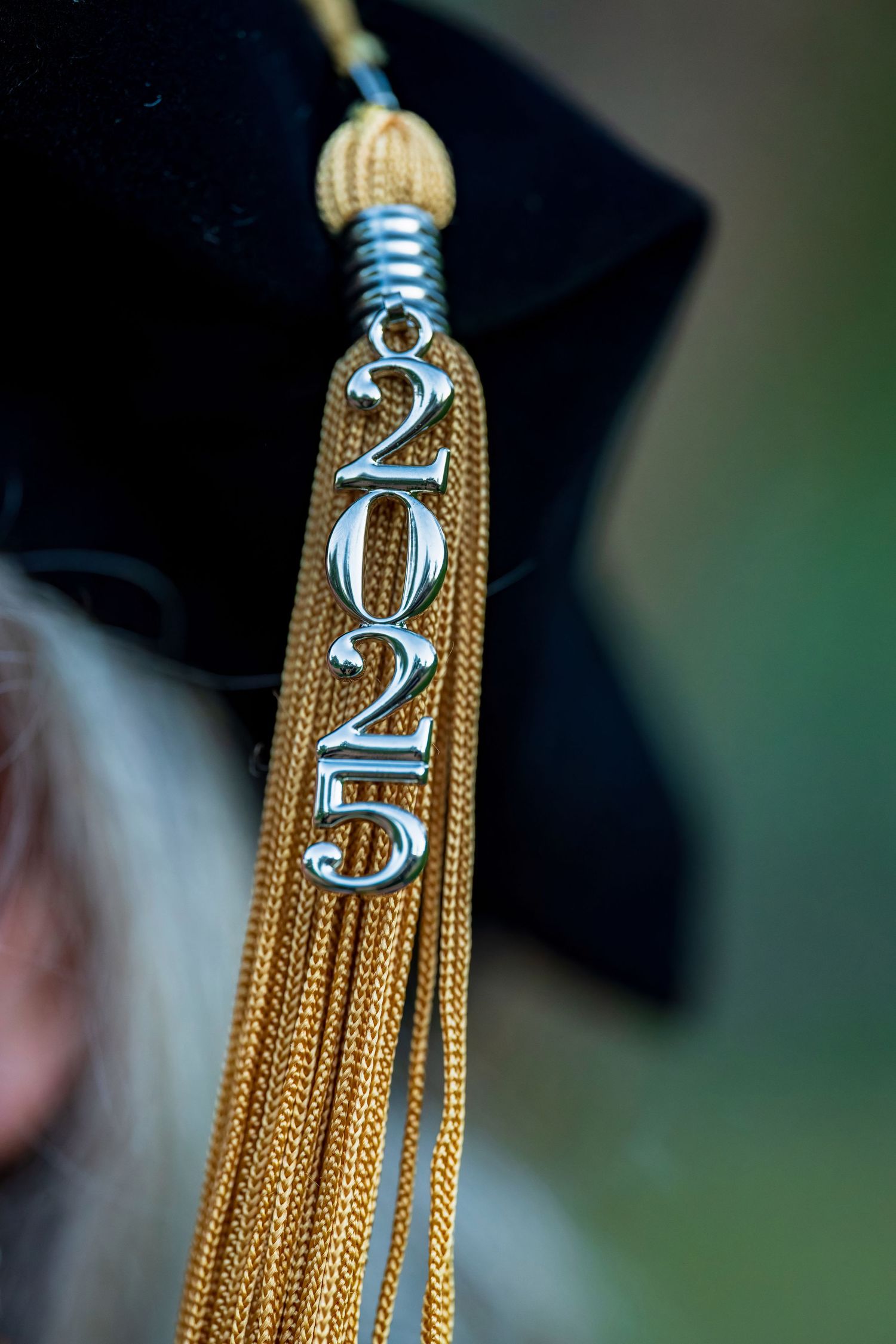 Gold graduation tassel with 2022 charm against blurred background.