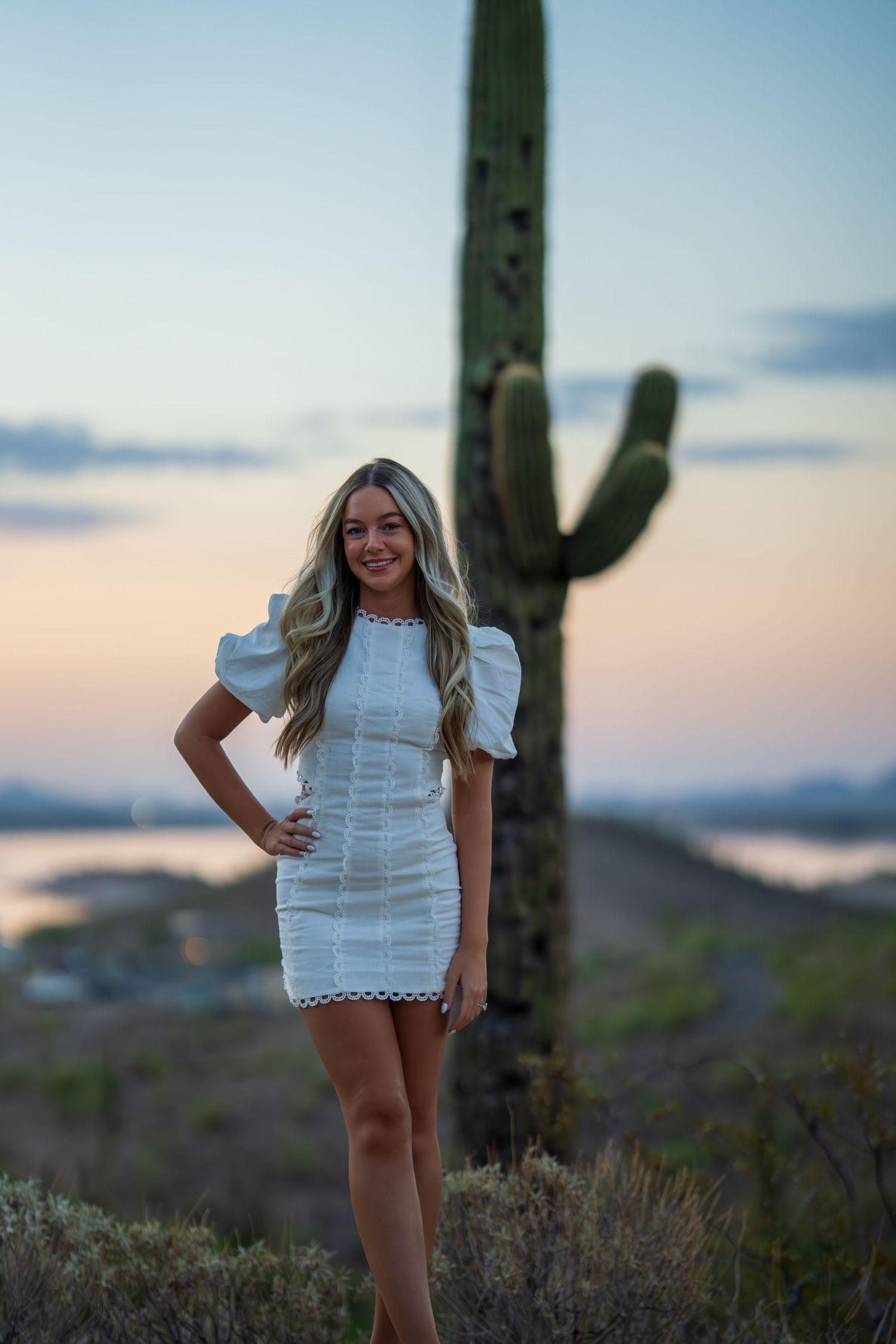 White summer dress photoshoot against desert mountain backdrop at dusk.
