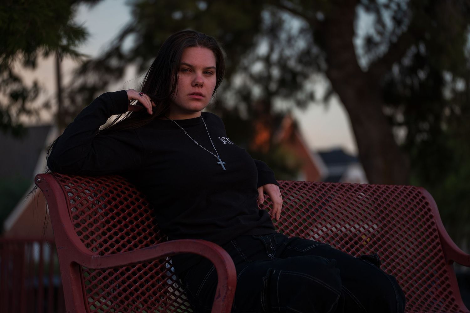 Artistic outdoor portrait with dramatic lighting and red bench composition.