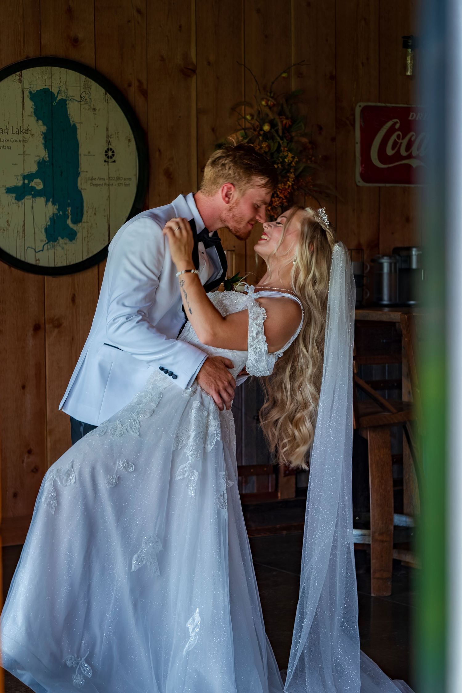 Elegant dance dip in rustic venue with Coca-Cola sign visible.