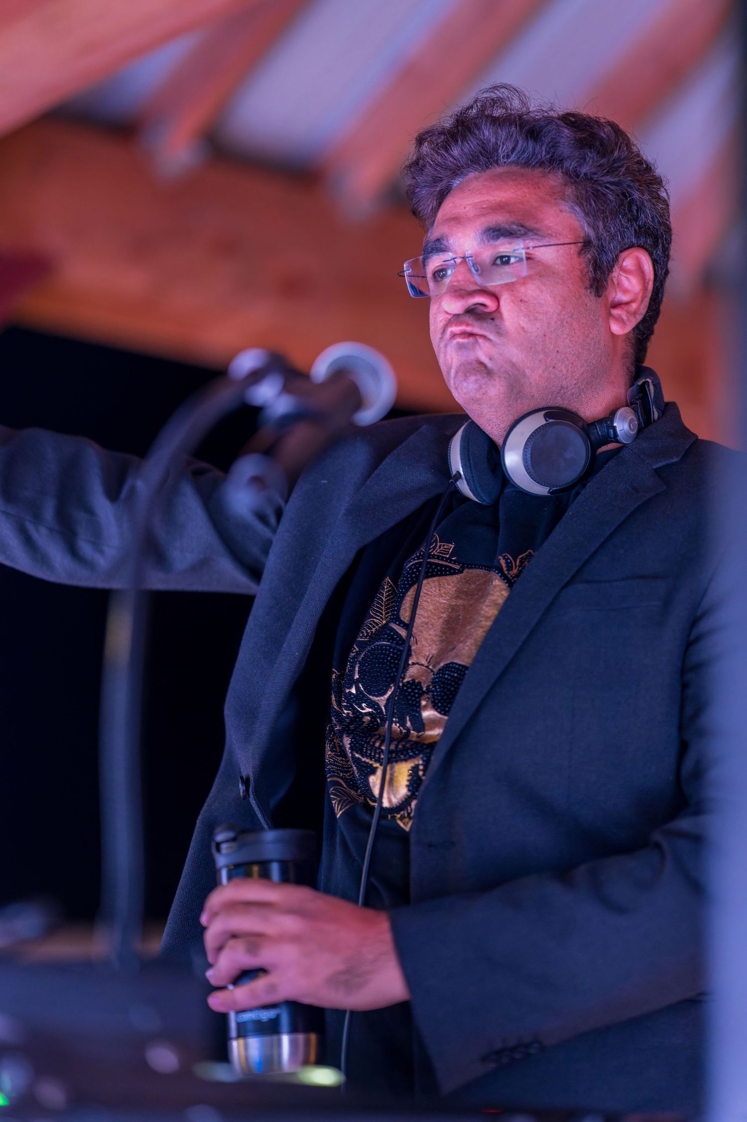 DJ performing at an event wearing black attire with professional audio equipment.