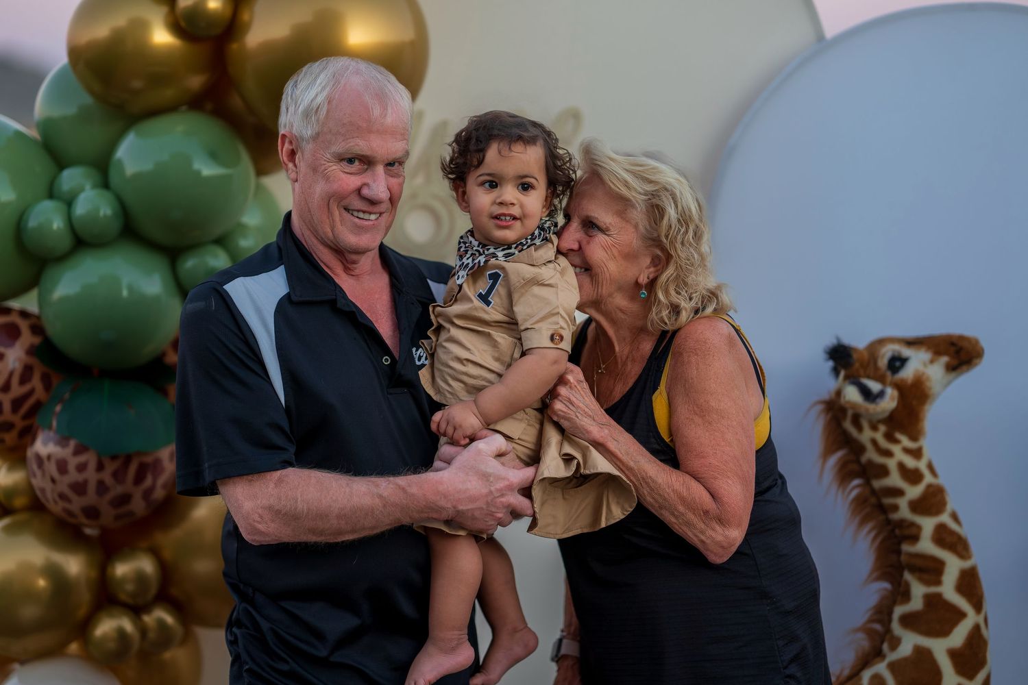 Candid moment at safari-themed birthday celebration with balloon arch and decorations.