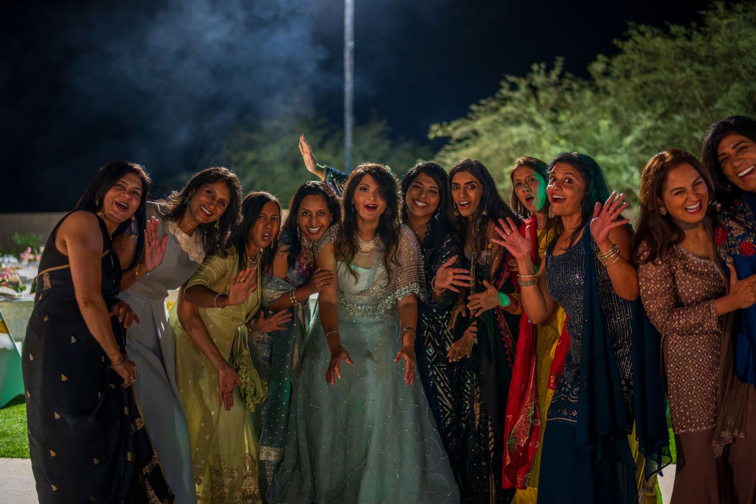 A group poses together during an evening celebration with atmospheric lighting.