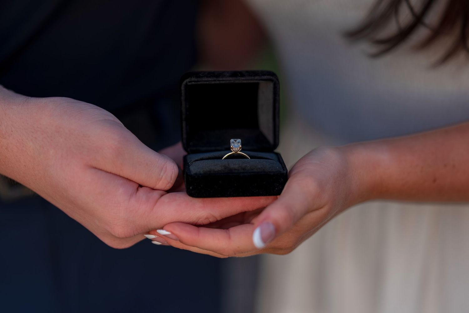 Close-up shots of hands exchanging a ring during a desert proposal.