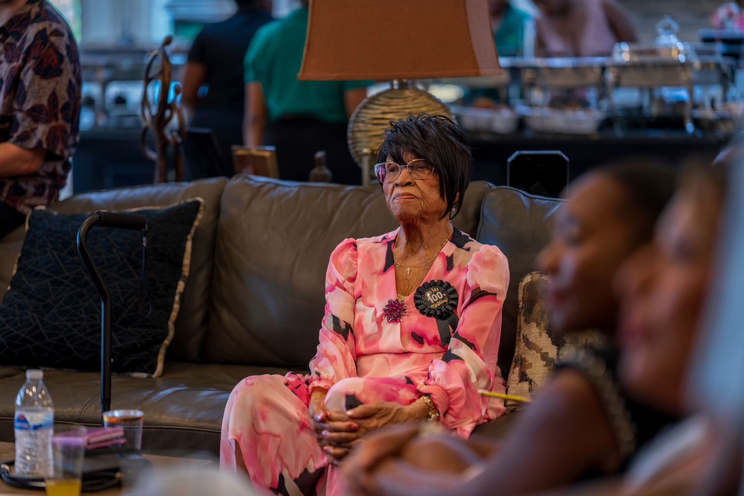 A guest in a pink outfit relaxes on a couch during a celebration.