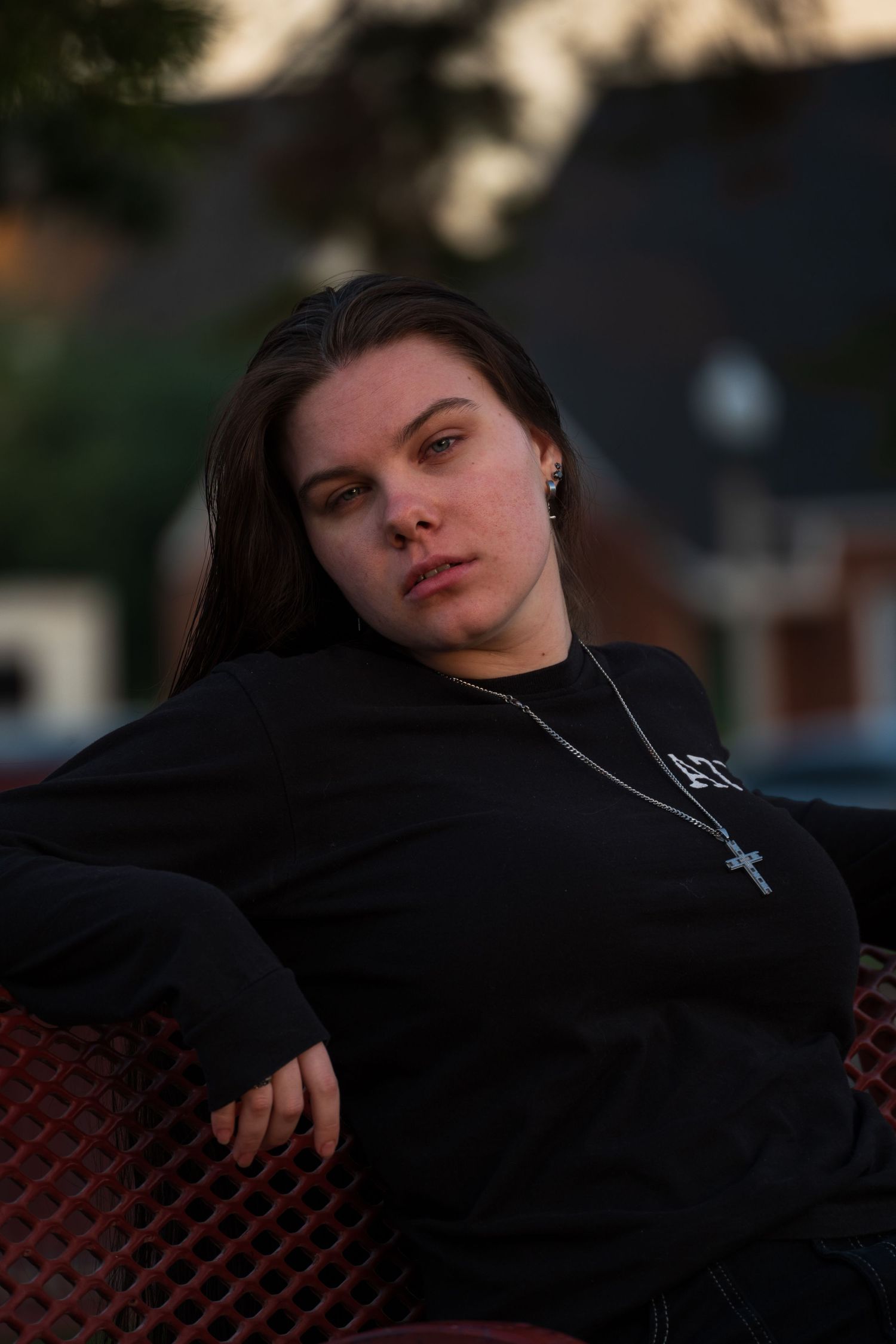 Moody outdoor photography with subject reclining on red bench at dusk.