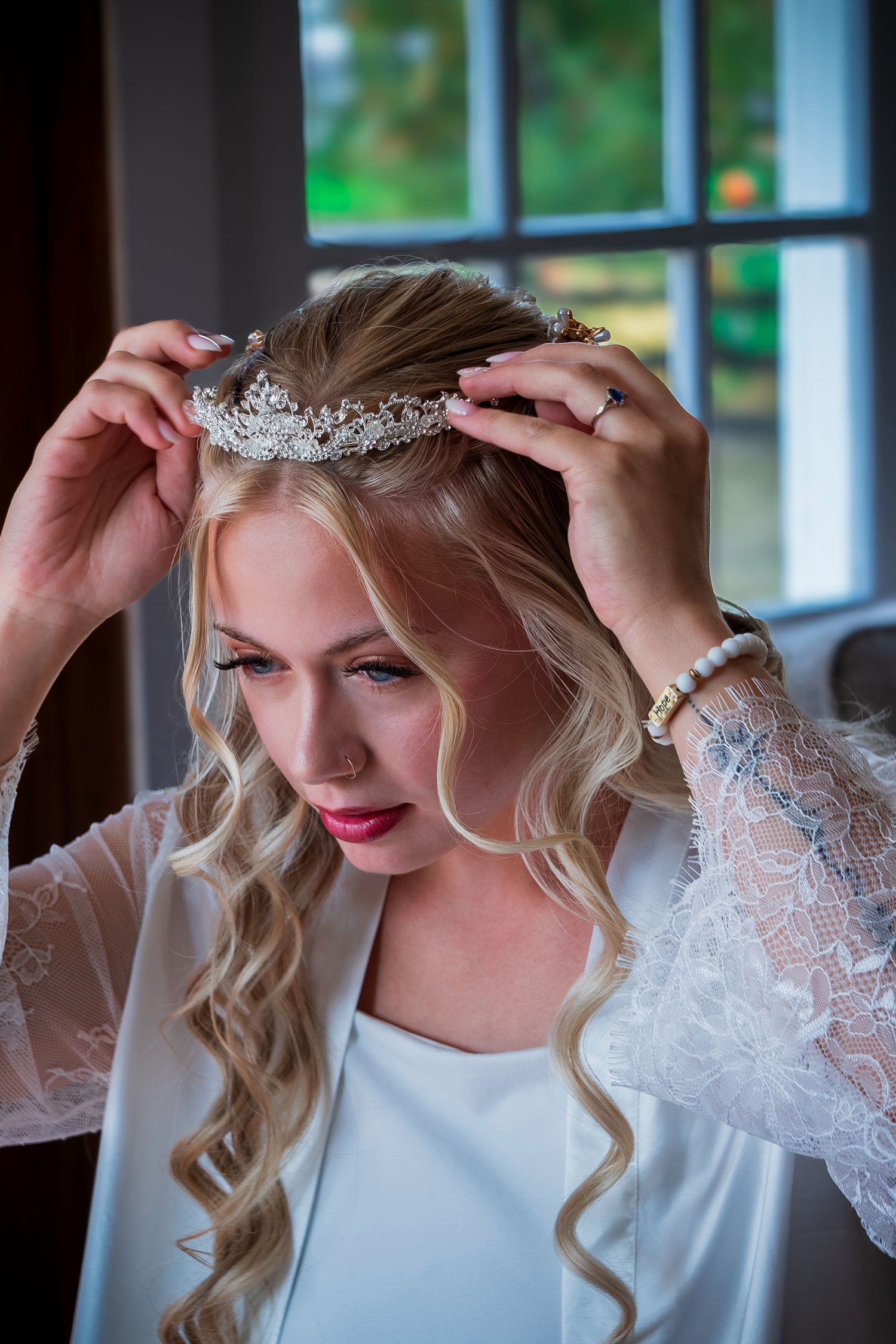 Delicate placement of bridal tiara on styled blonde hair.