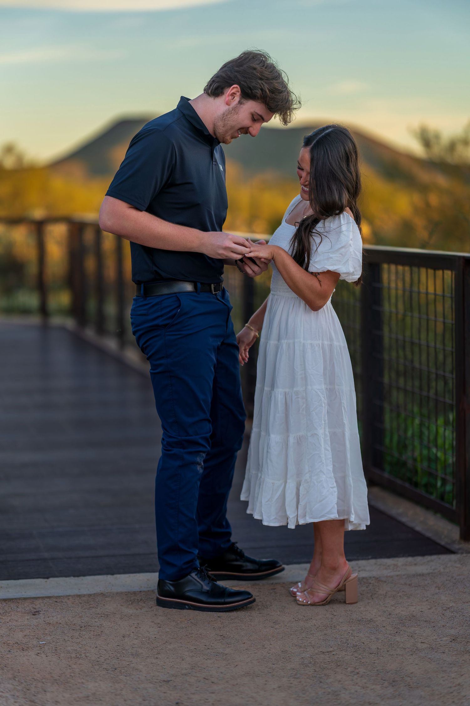 A romantic scene unfolds between two people on an outdoor deck with desert landscape behind them.