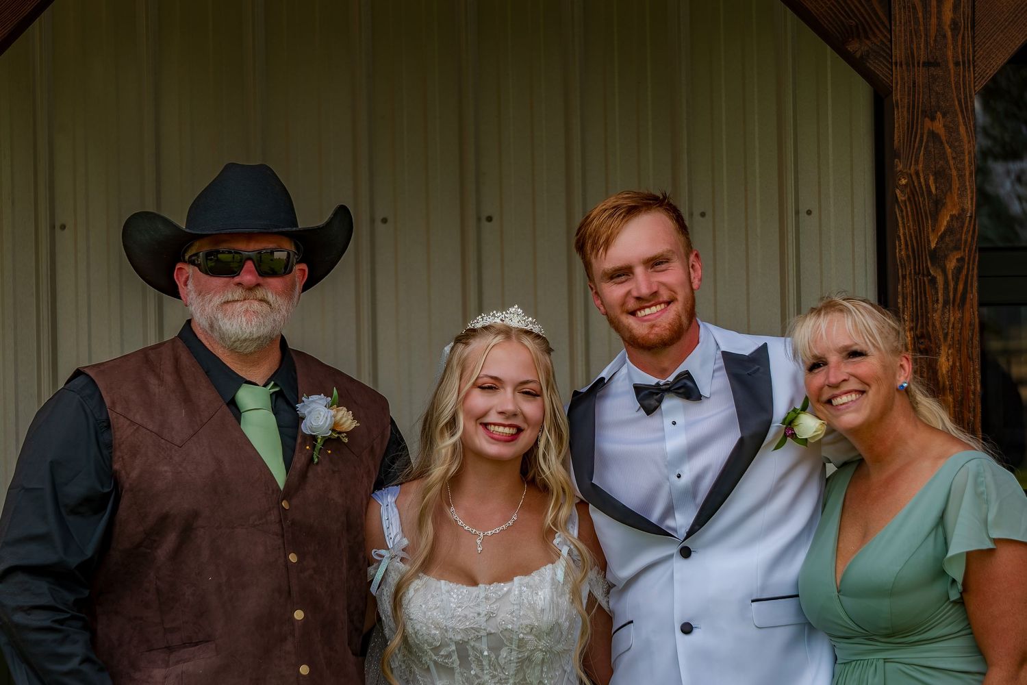 Wedding party members in country western attire gather for group photos at rustic venue.