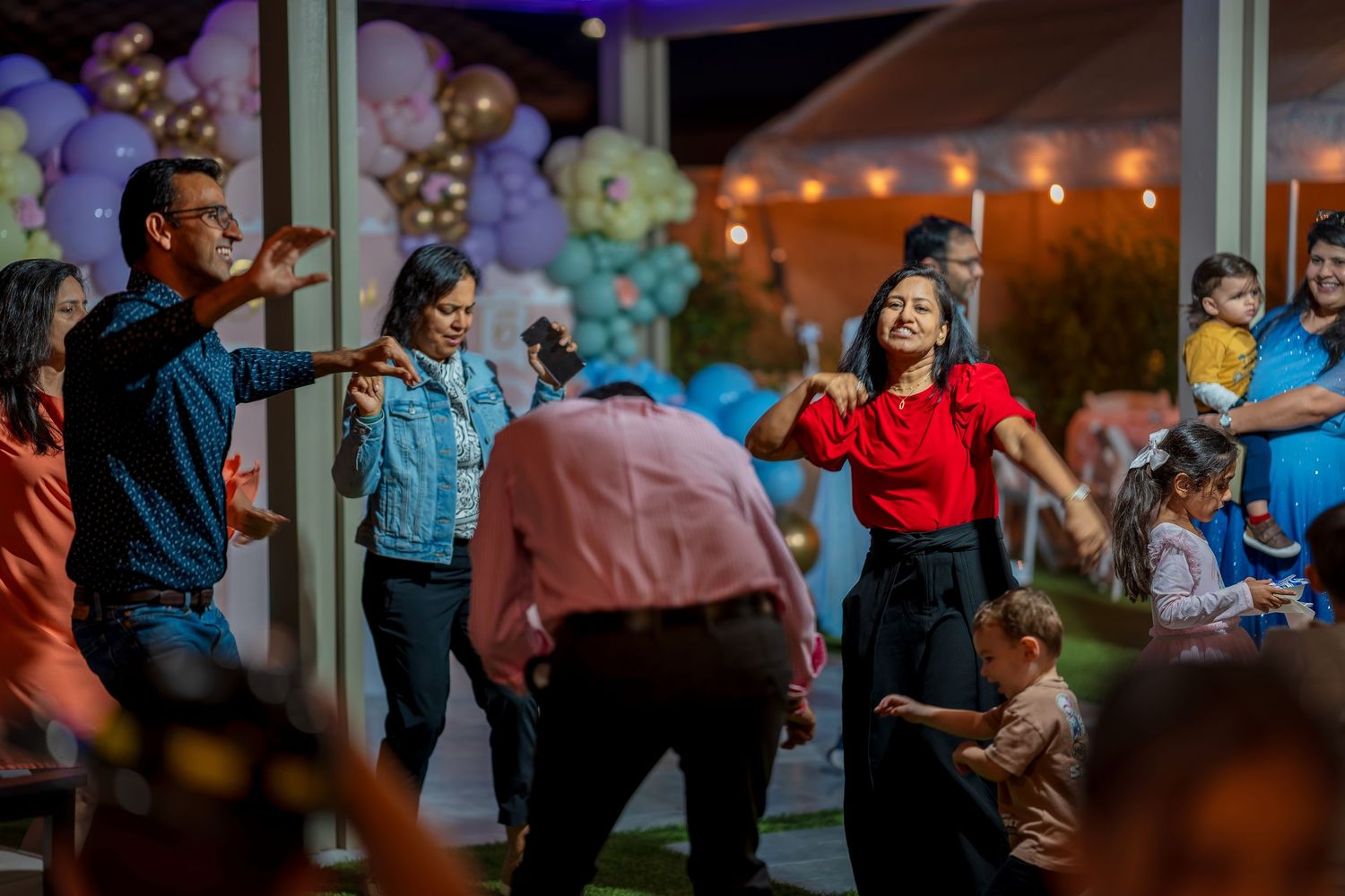 Guests dancing and celebrating at an evening party with balloon decorations in the background.