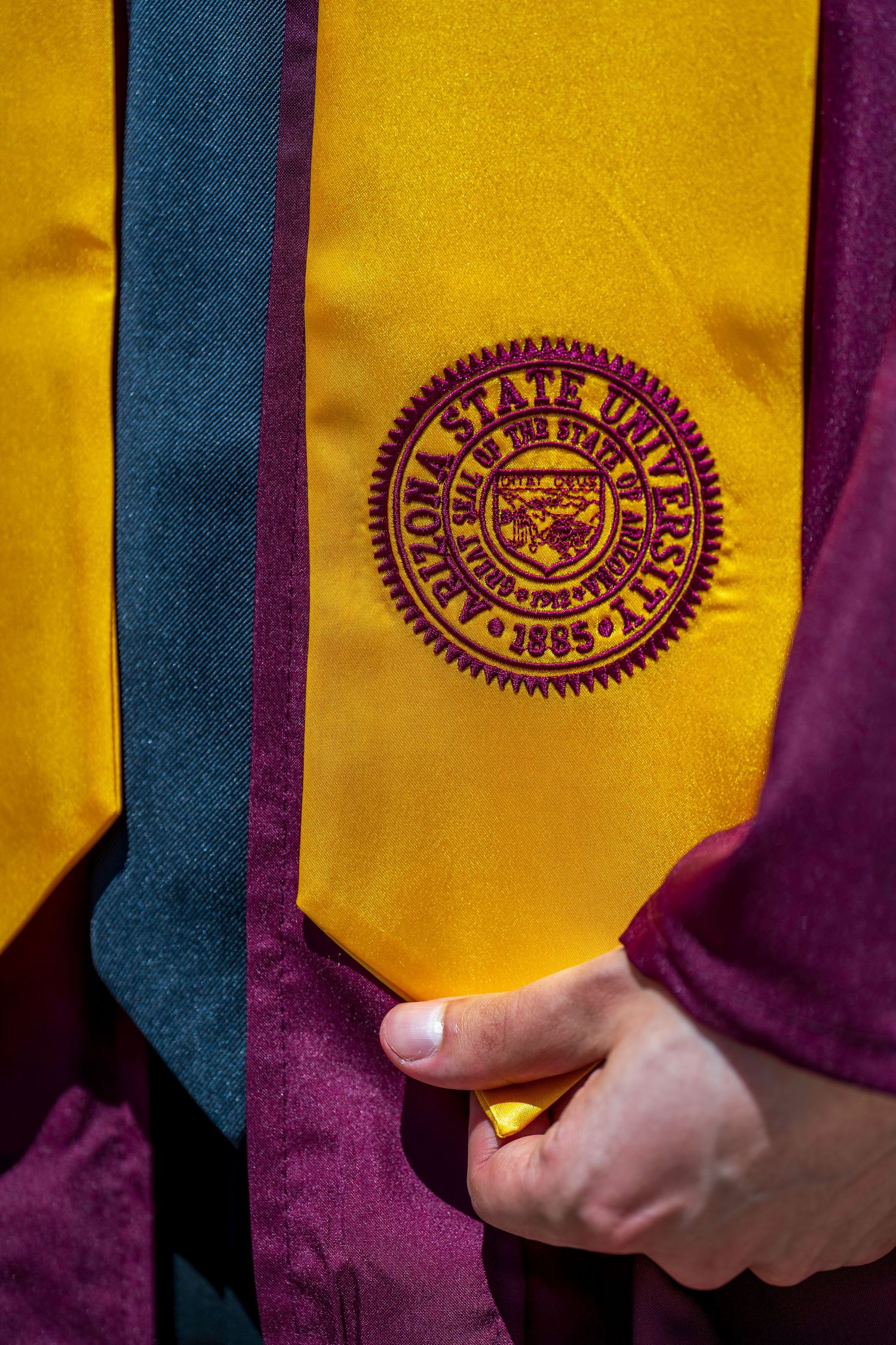 Close-up of an Arizona State University gold stole with embroidered maroon ASU seal, founded 1885.