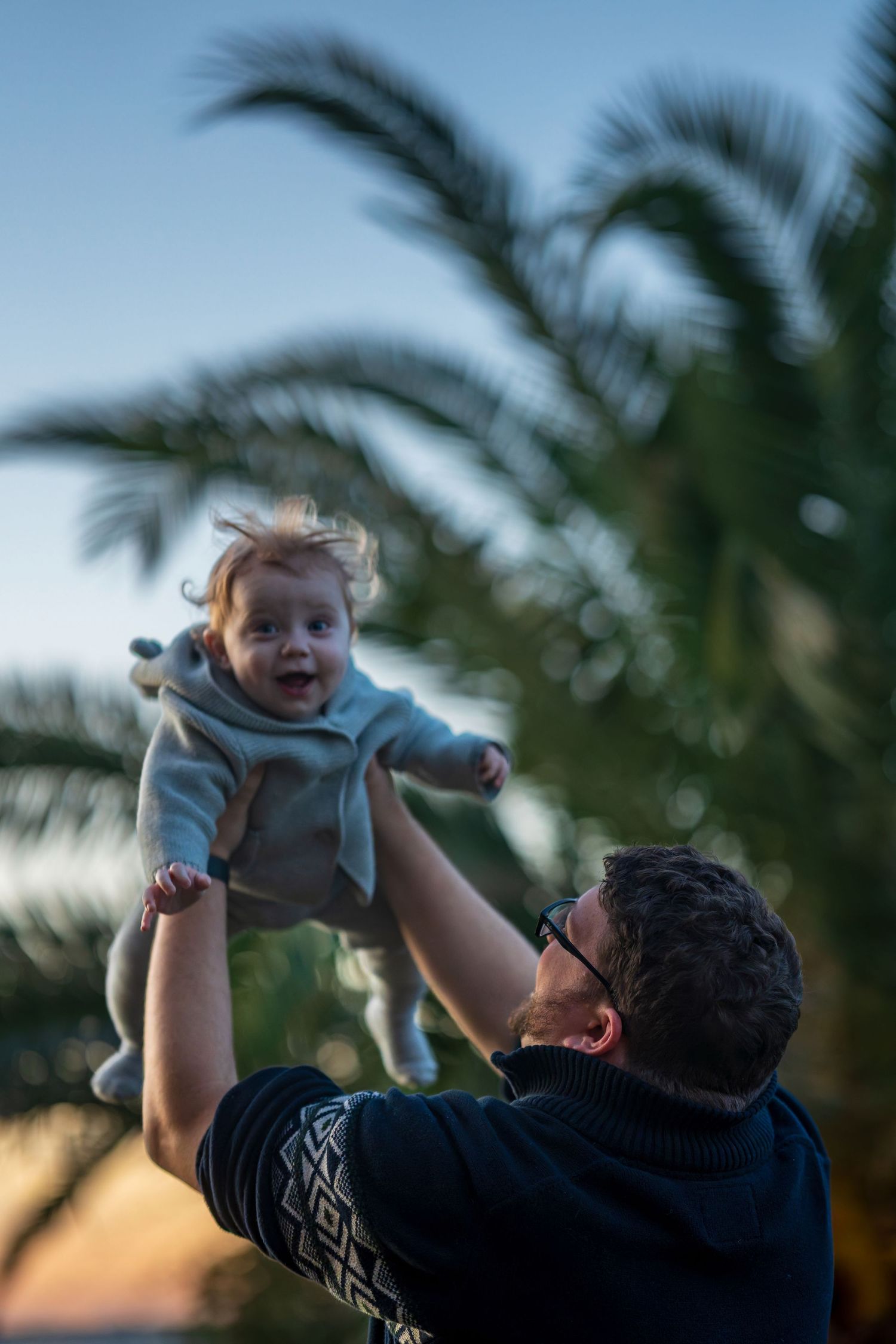 Playful moment captured at sunset with palm trees in background.