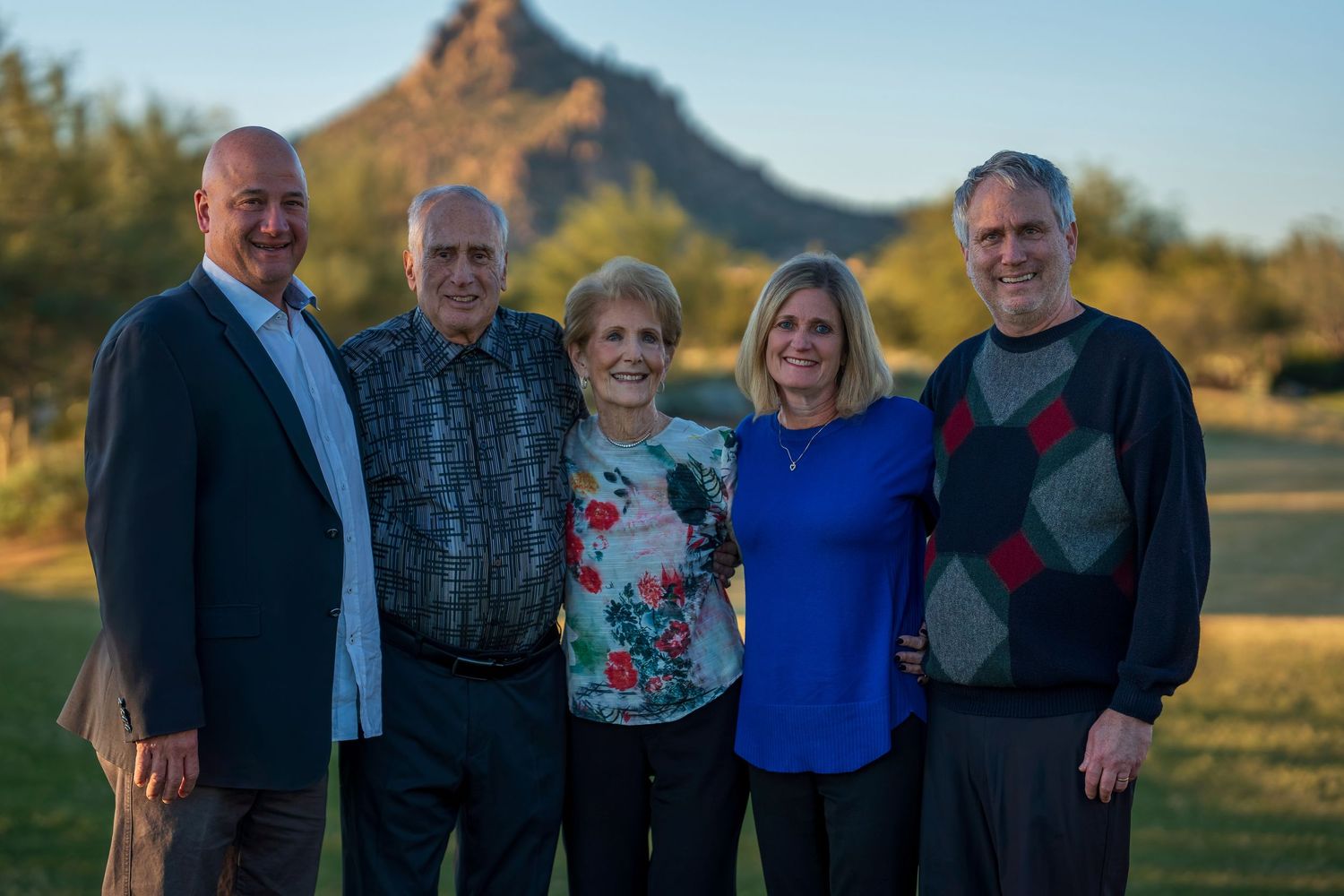 Extended family group photo taken outdoors with mountain landscape in background.