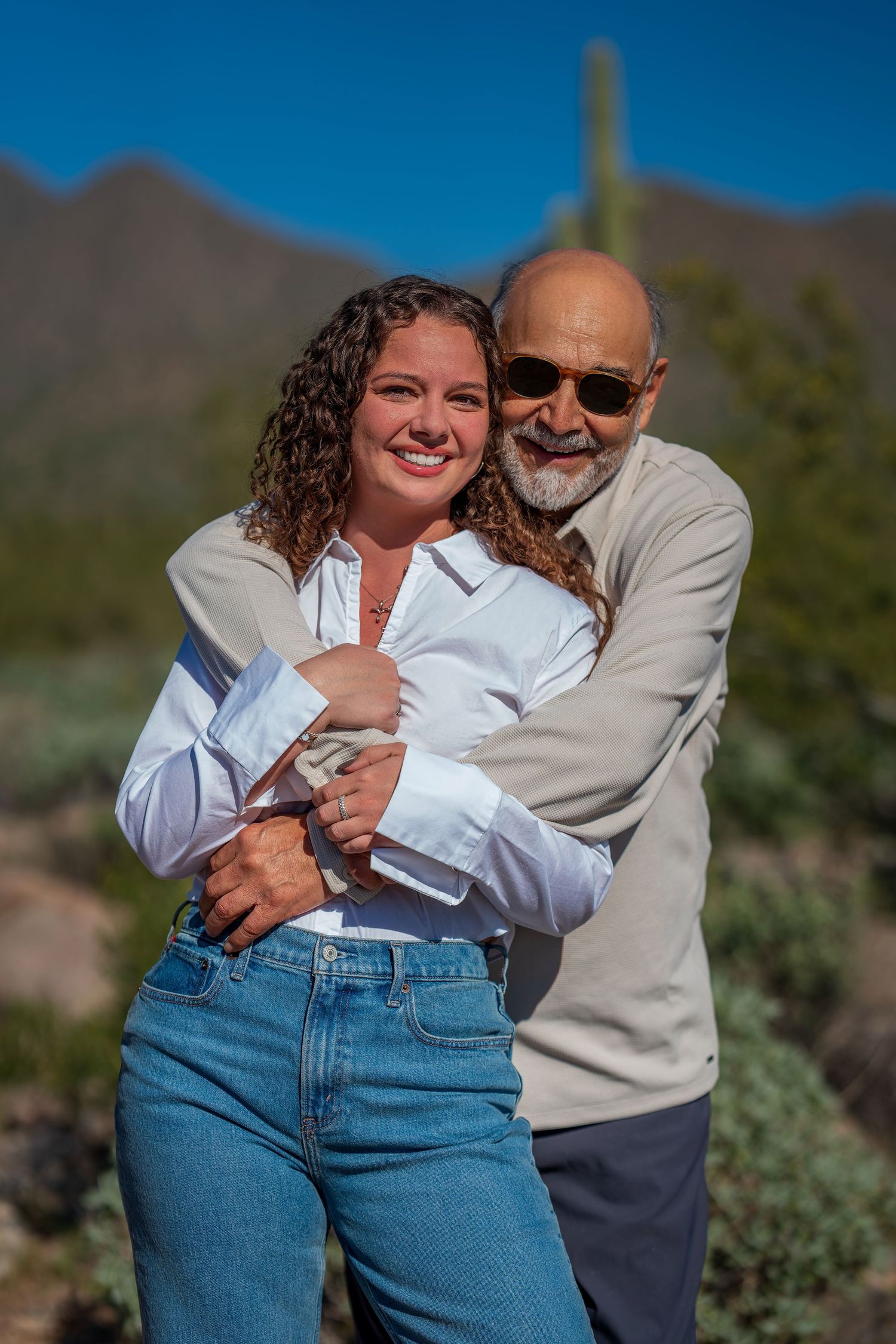 A sweet embrace captured against a desert mountain backdrop with saguaro cactus.