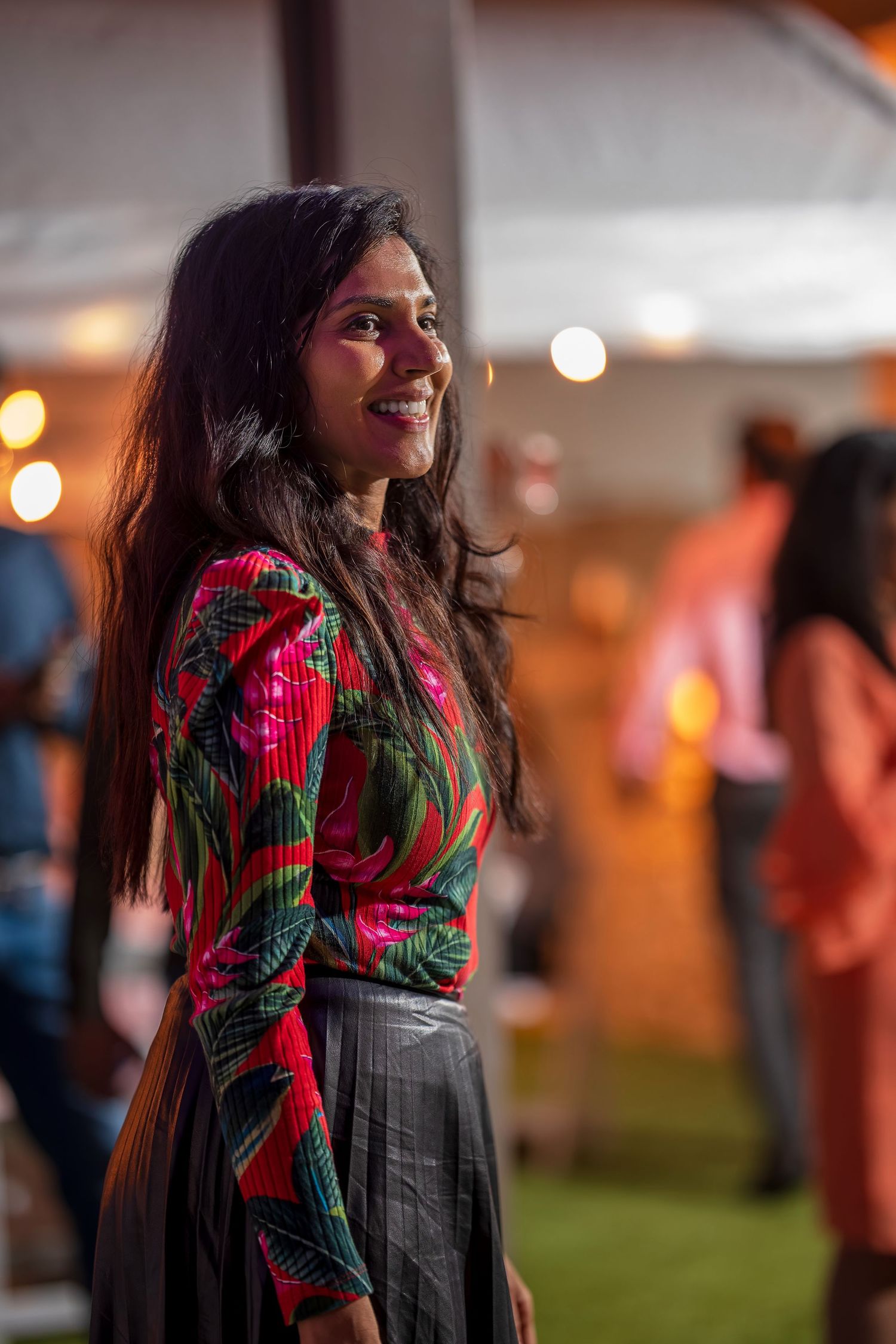Someone in a festive red and green floral print top dances at a party.