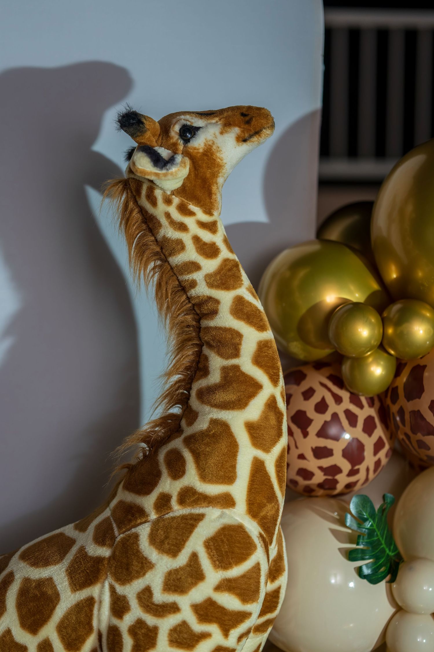 A decorative plush giraffe display with gold balloons in the background.