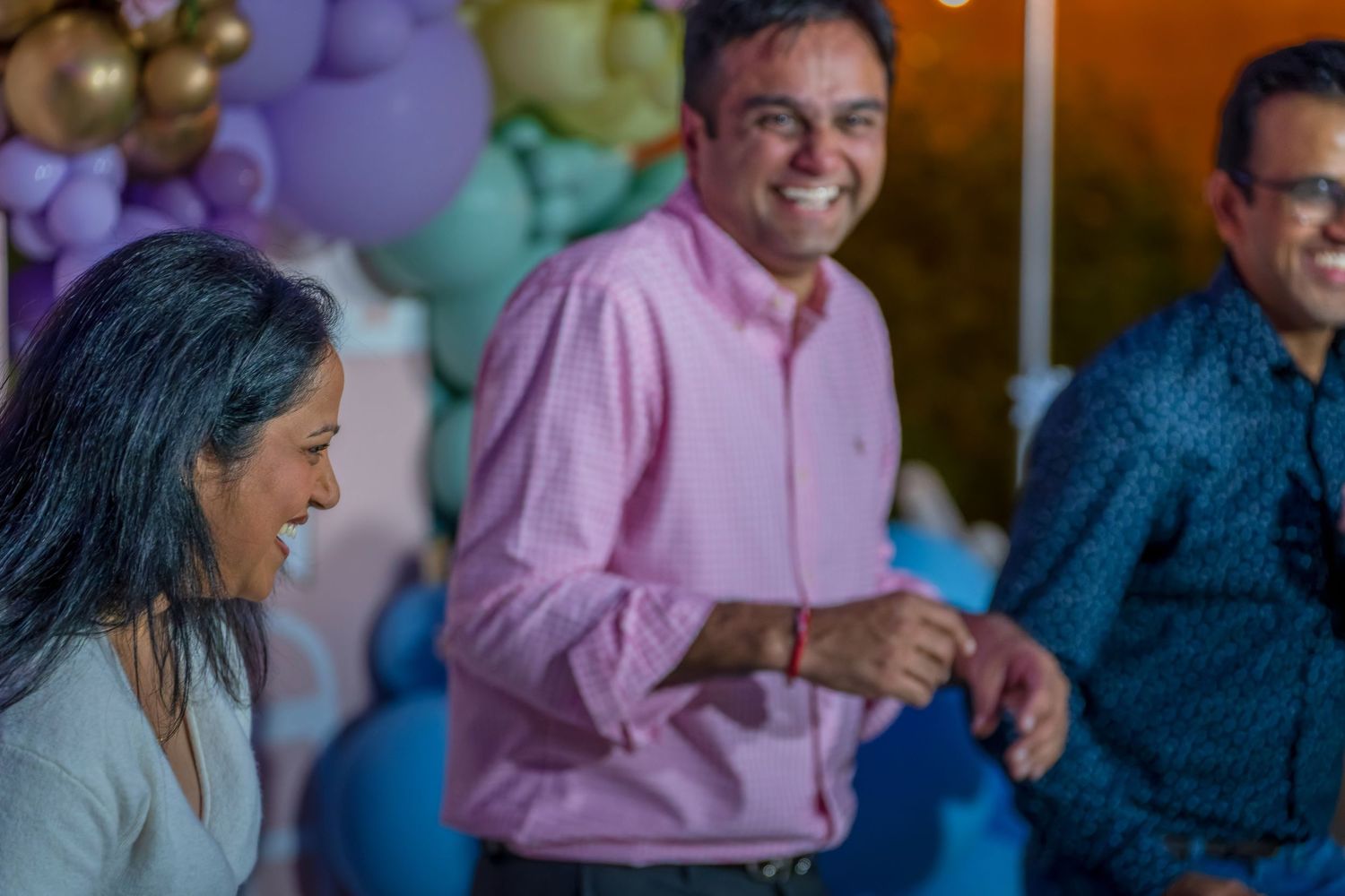 Guests enjoying a festive celebration with colorful balloon arrangements and ambient lighting.