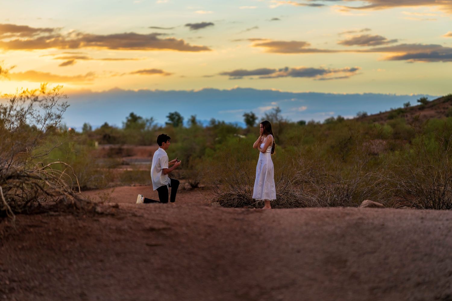 A couple shares a special moment on a desert hilltop during sunset.
