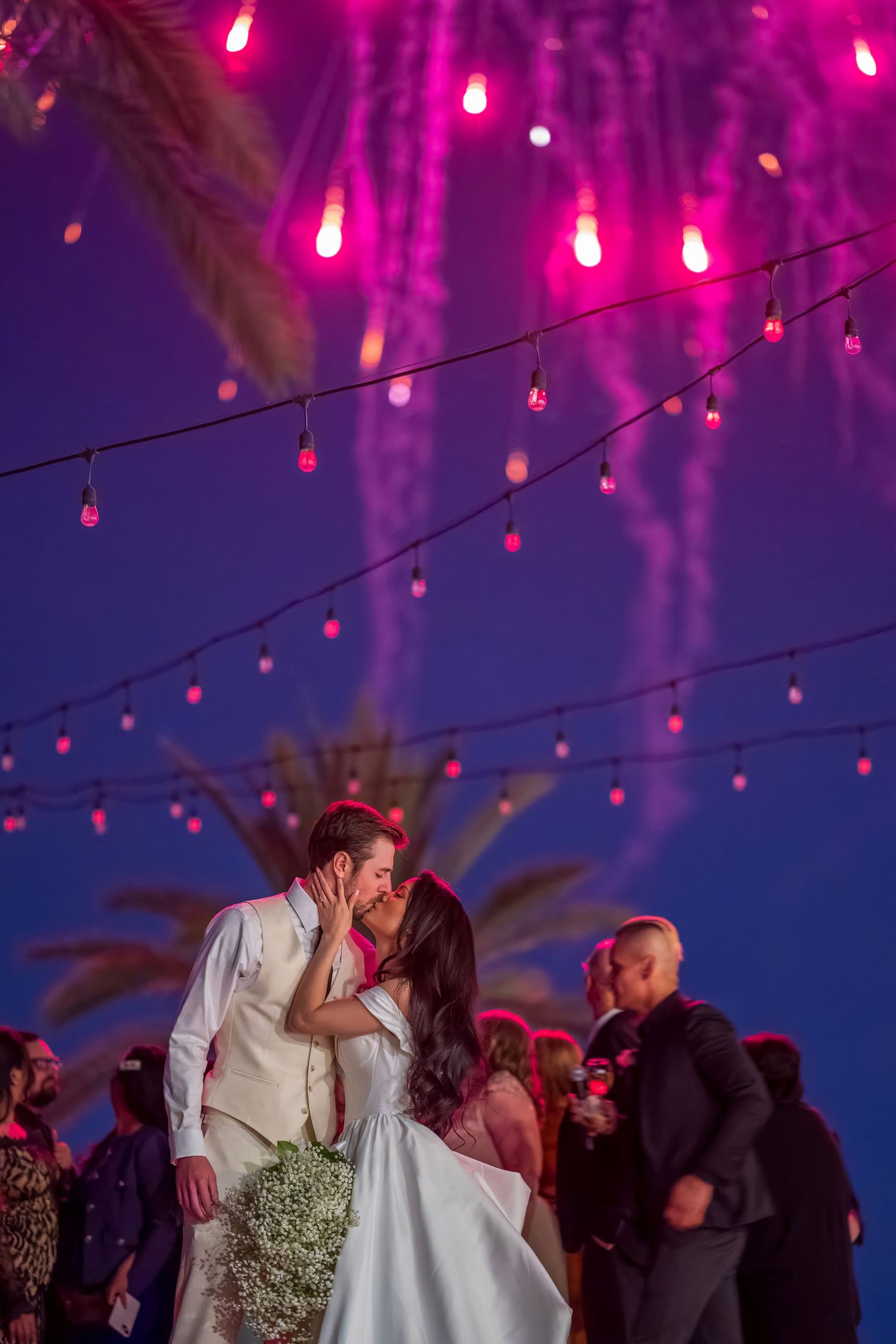 Wedding celebration under purple string lights creating a magical evening atmosphere.