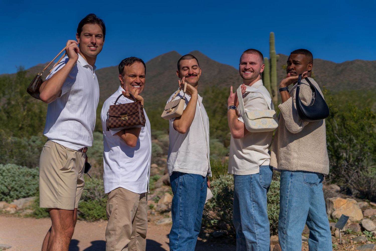Friends gathered for group photo in desert setting with mountains and cacti.