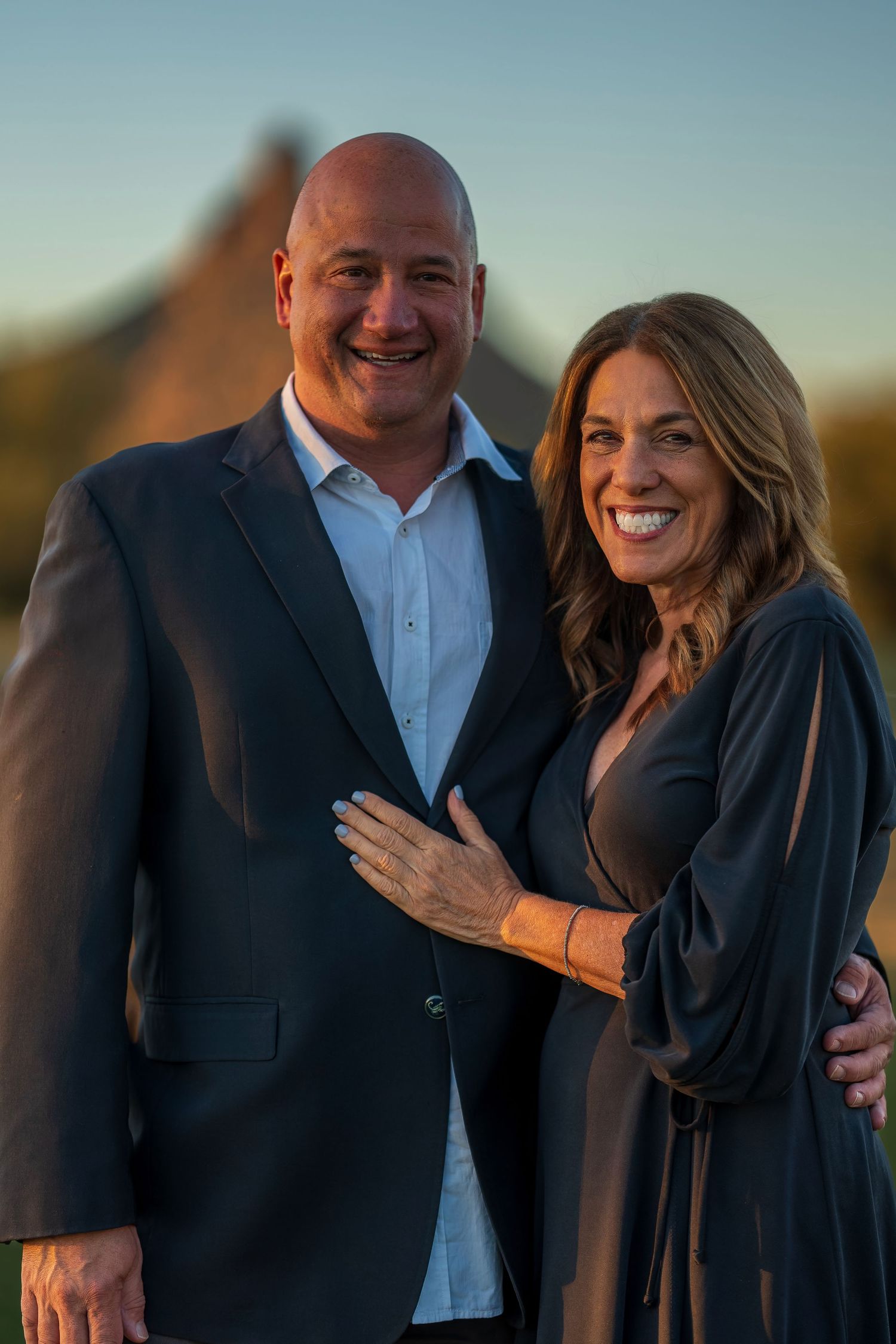 Couple in formal attire sharing intimate moment during outdoor sunset photo session.