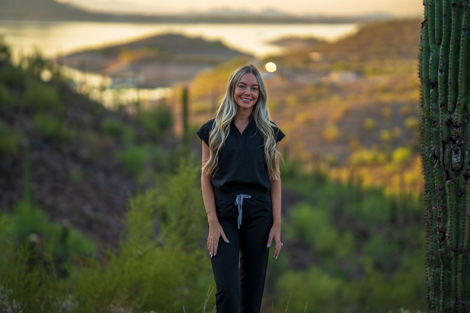 Casual black outfit photographed in desert landscape with saguaro cactus at sunset.